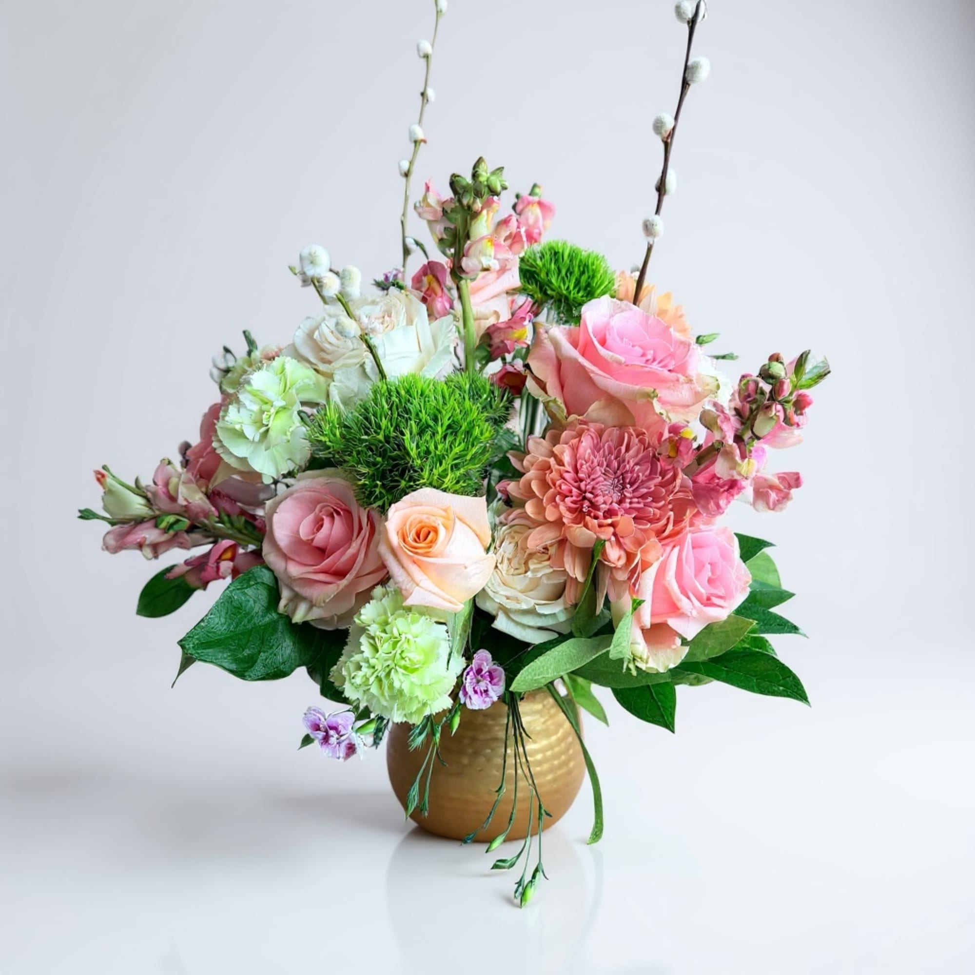 Pink and peach floral arrangement in a gold vase