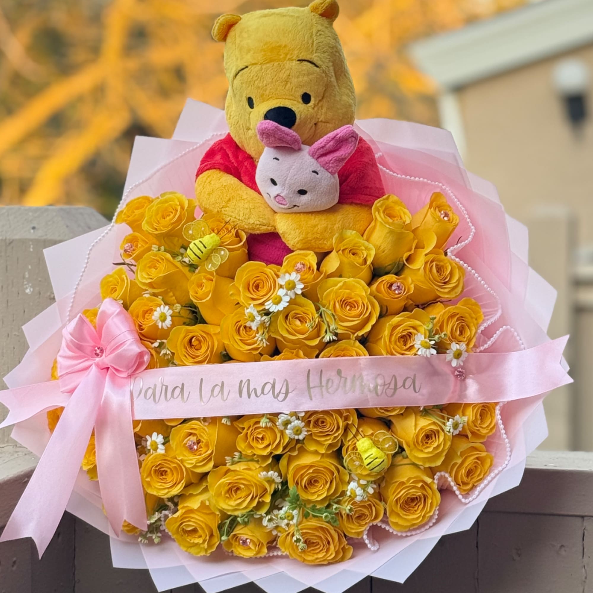 Bouquet of yellow roses with a Winnie the Pooh plush and pink ribbon
