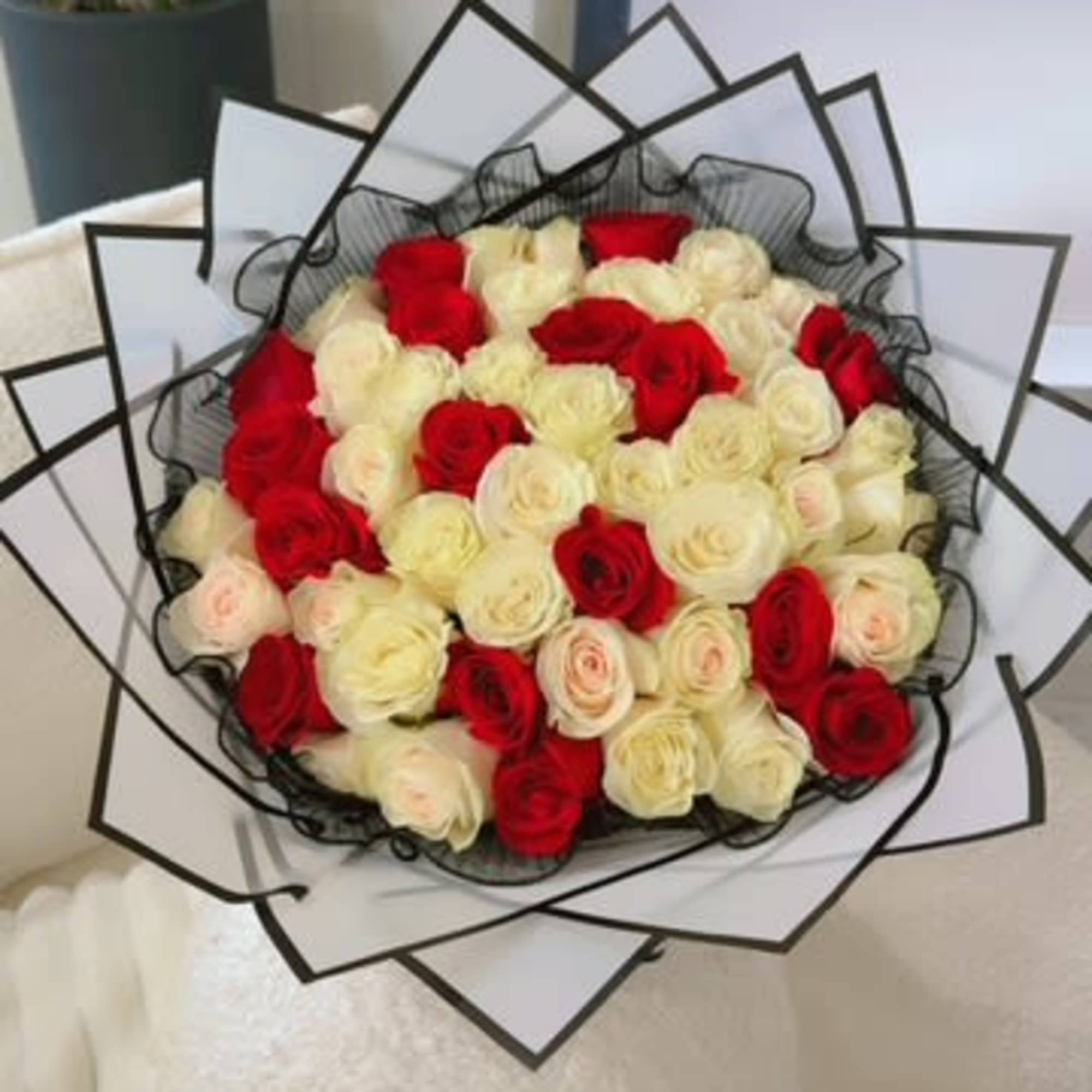 Bouquet of red and cream roses wrapped in black-edged paper