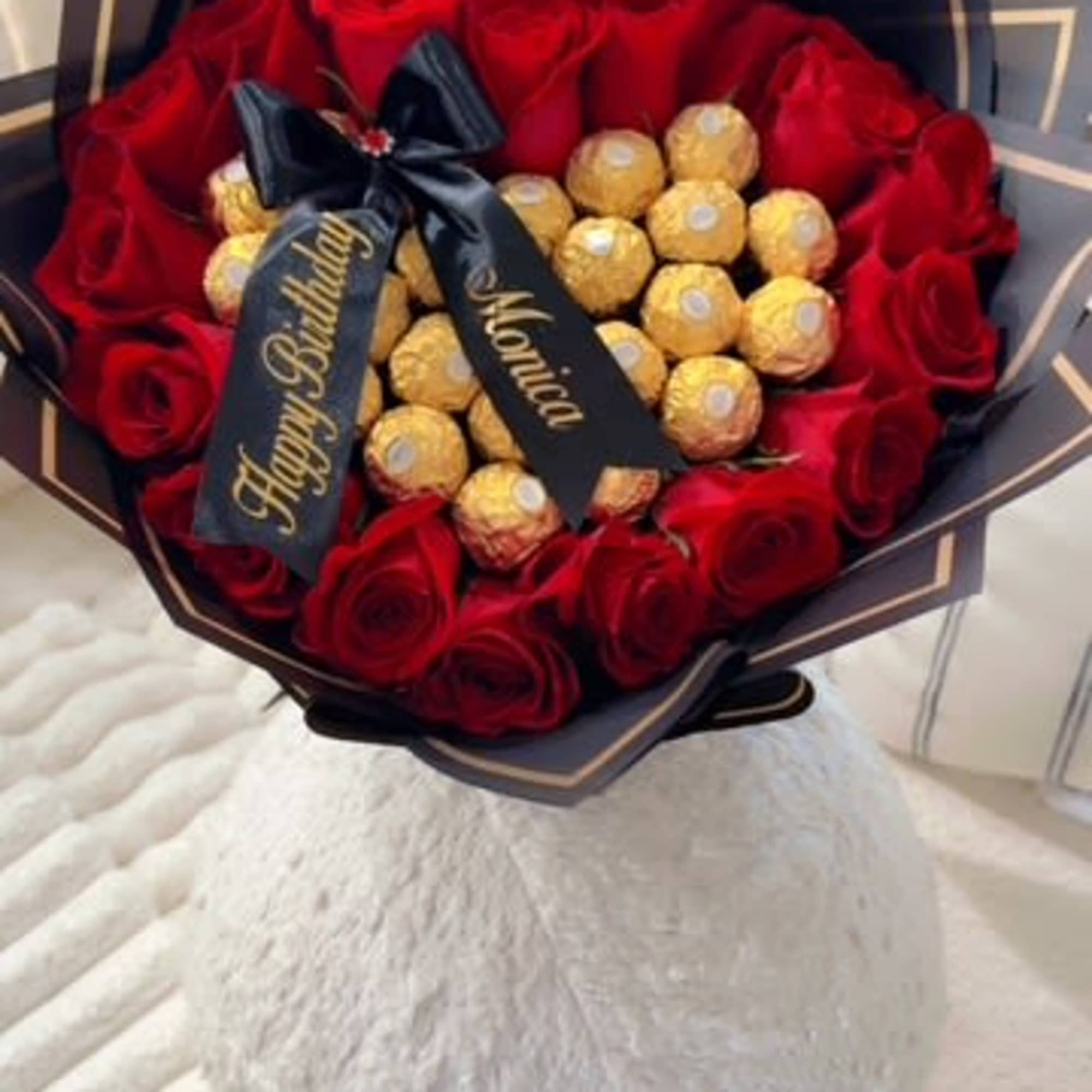 Bouquet of red roses with gold-wrapped chocolates and a black ribbon
