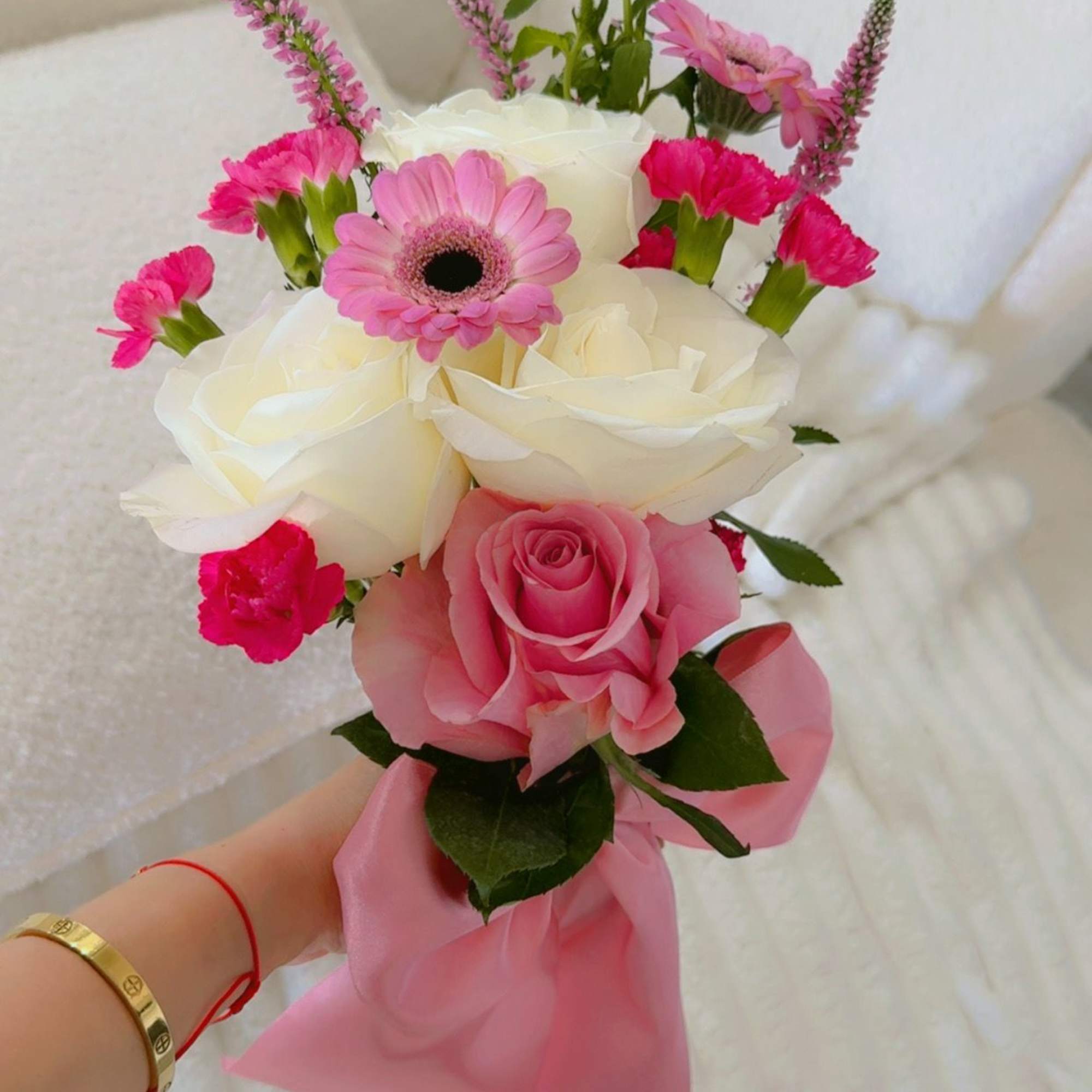 Pink and white bouquet with roses, a gerbera daisy, and small carnations