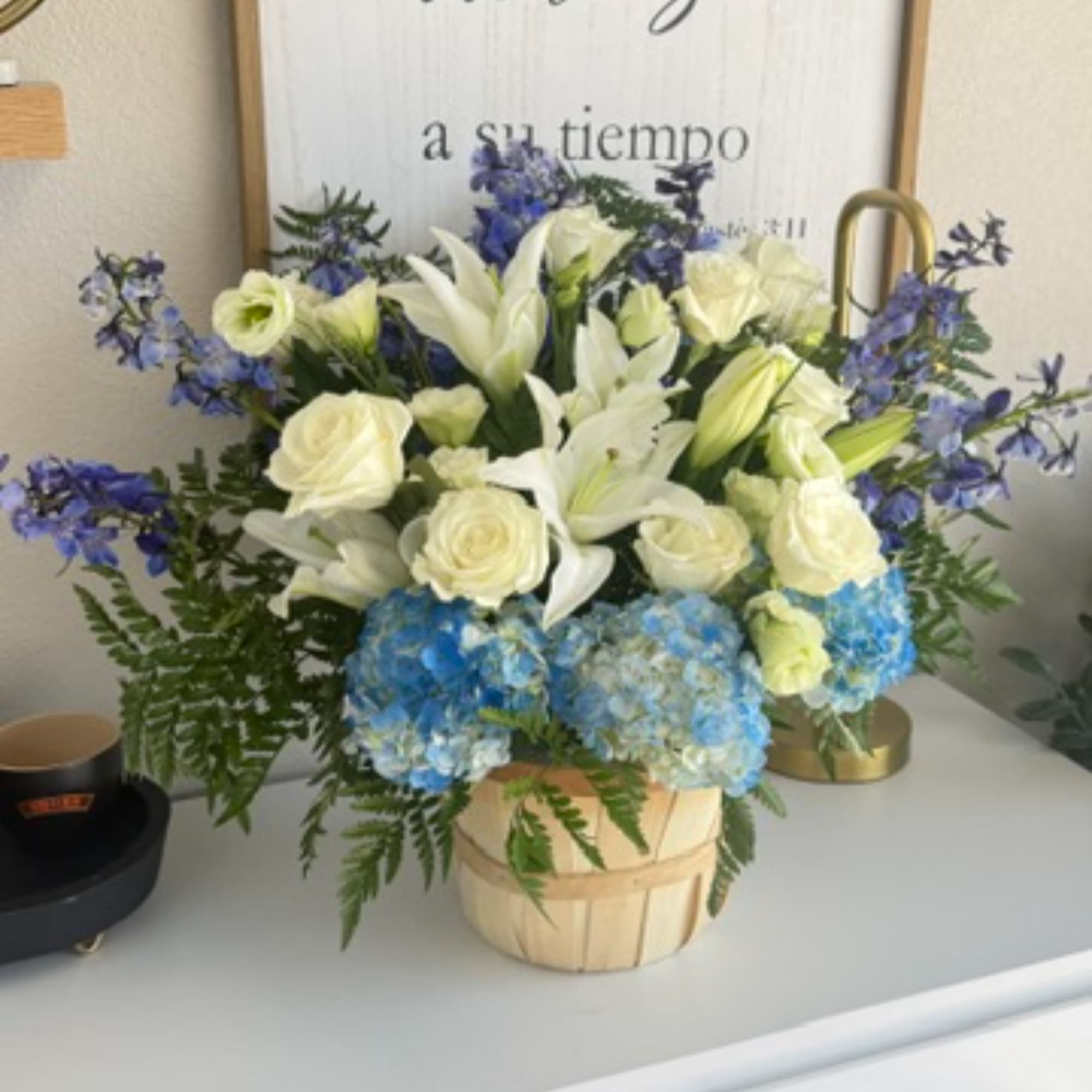 White lilies and roses with blue hydrangeas in a basket