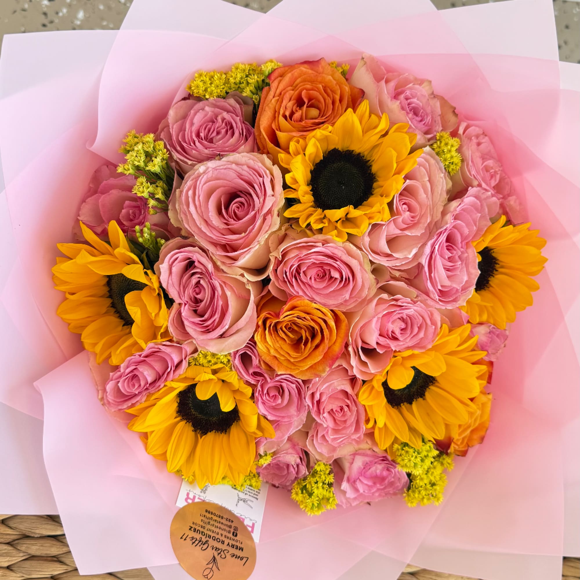 Bouquet of pink and orange roses with sunflowers wrapped in pink paper