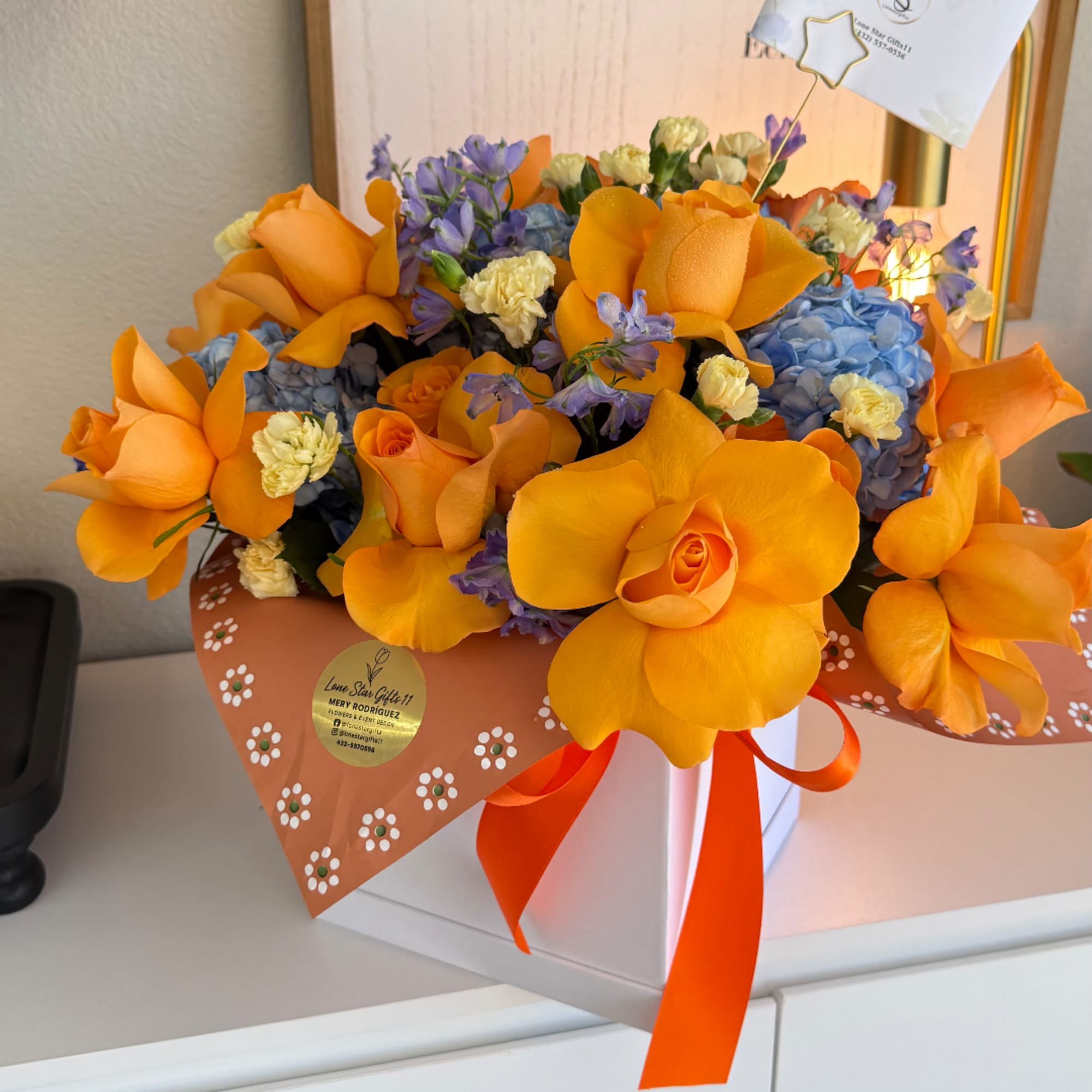 Orange roses and blue hydrangeas in a gift box with a ribbon
