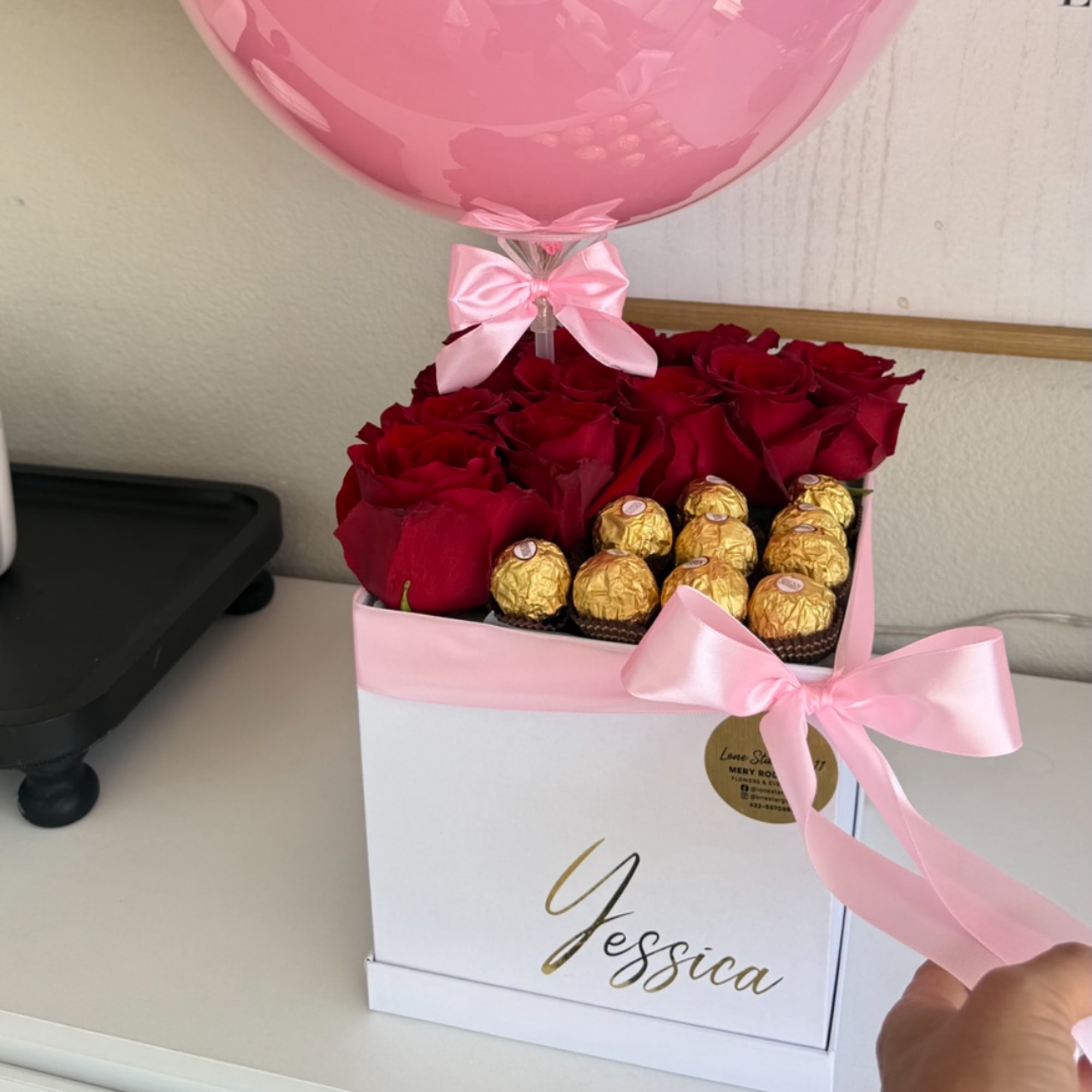Red roses and gold chocolates in a pink gift box with a pink balloon