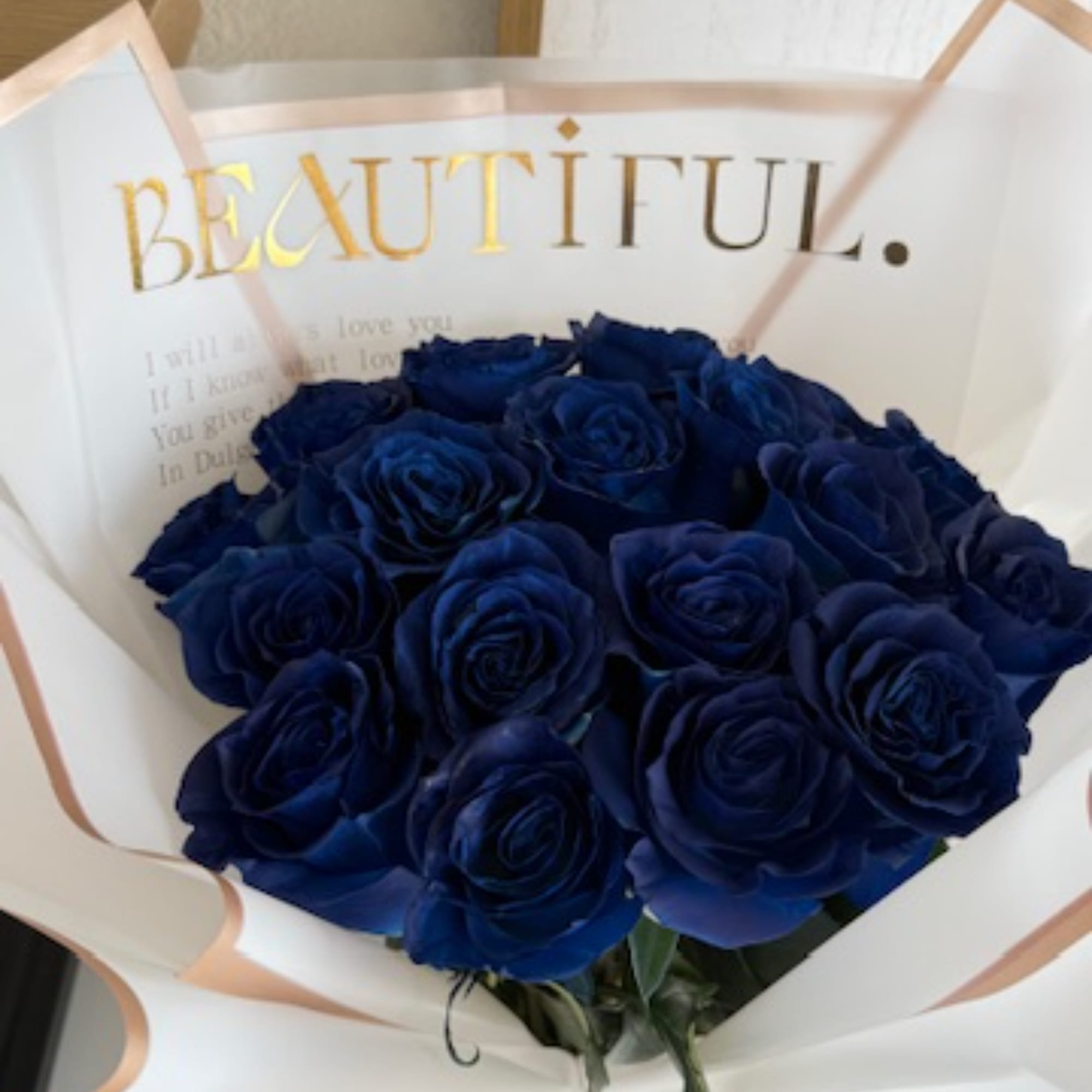 Bouquet of deep blue roses wrapped in white paper with gold lettering