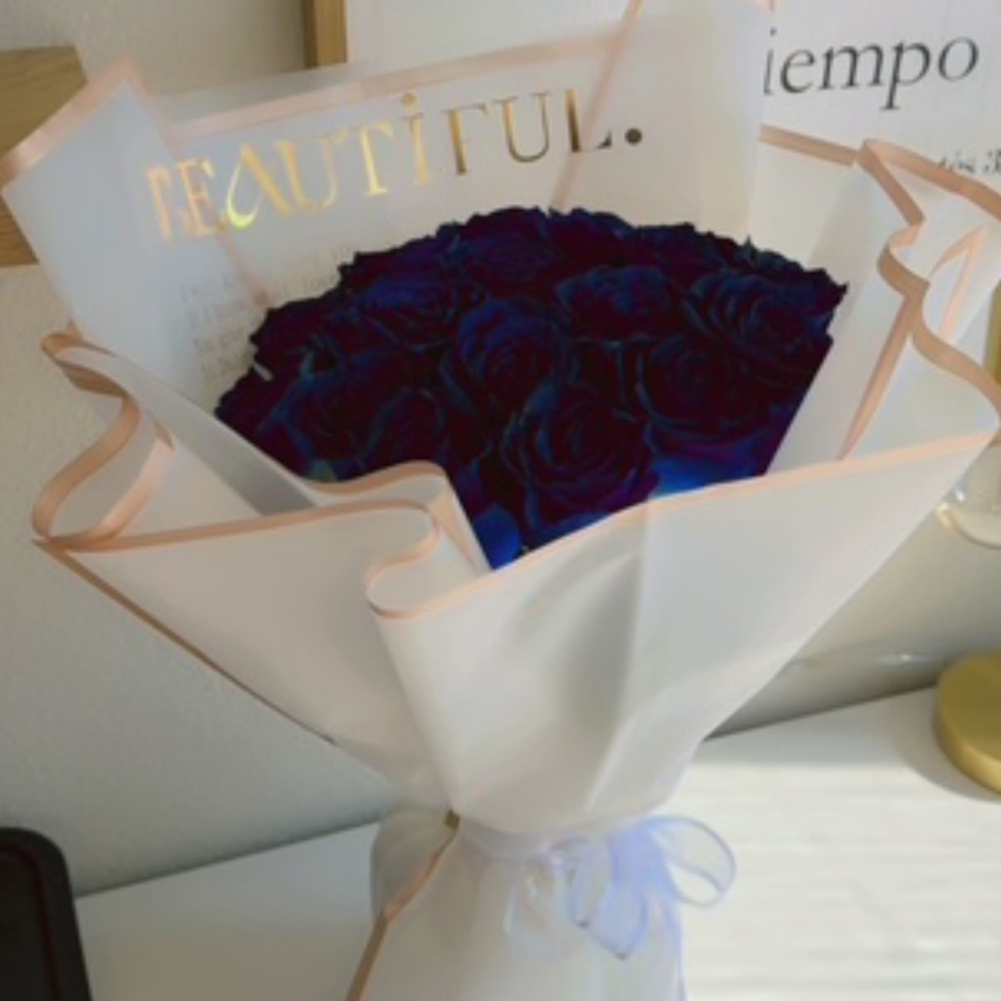 Bouquet of dark red roses wrapped in white paper with a ribbon