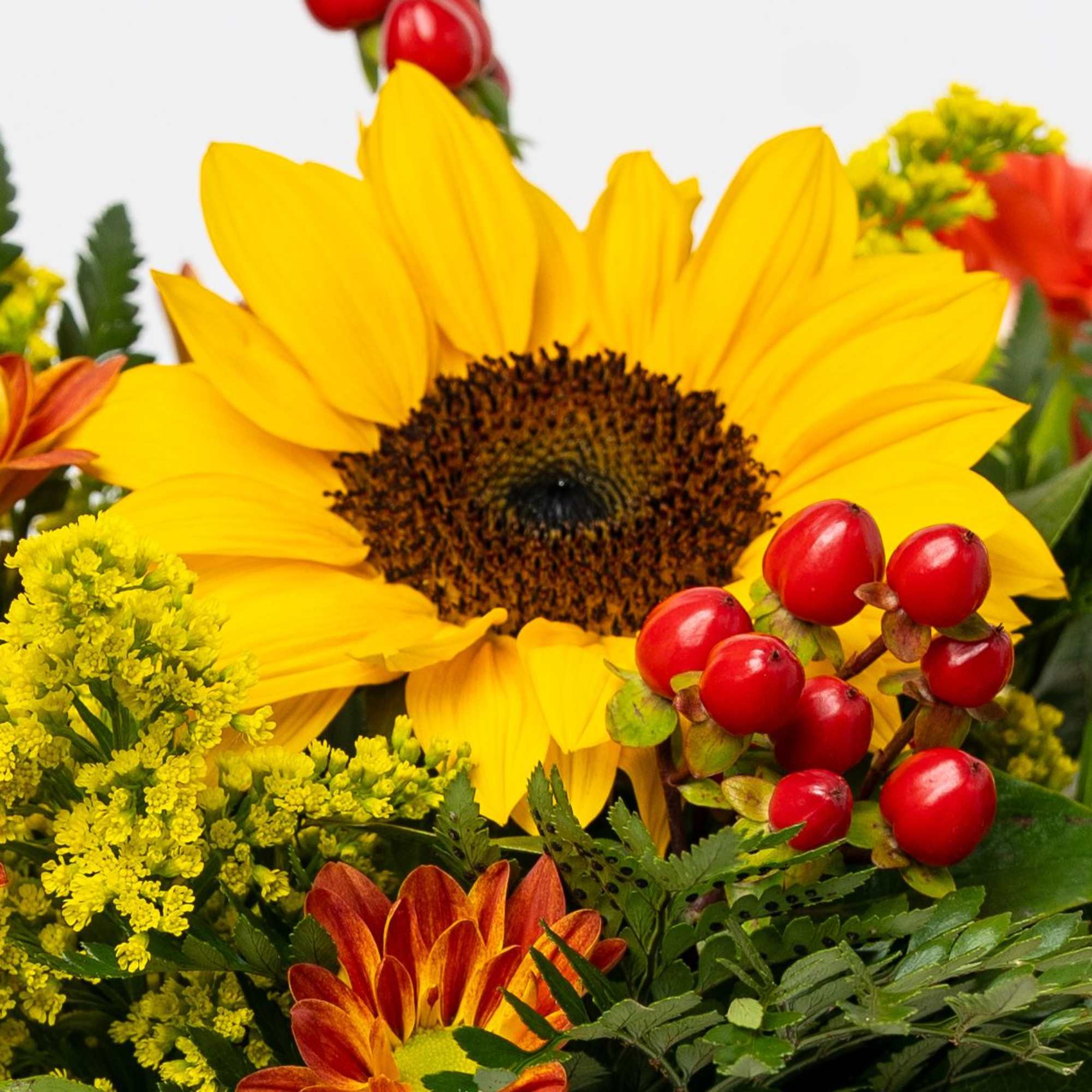 Sunflower bouquet with orange blooms and red berry accents