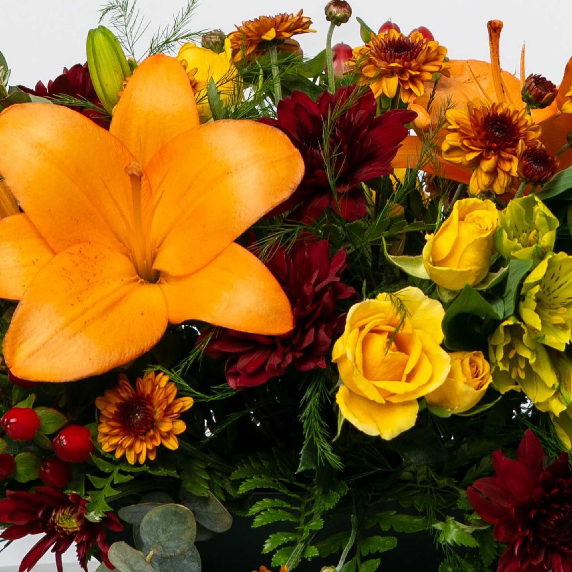 Orange lilies with yellow roses and burgundy chrysanthemums in a mixed bouquet