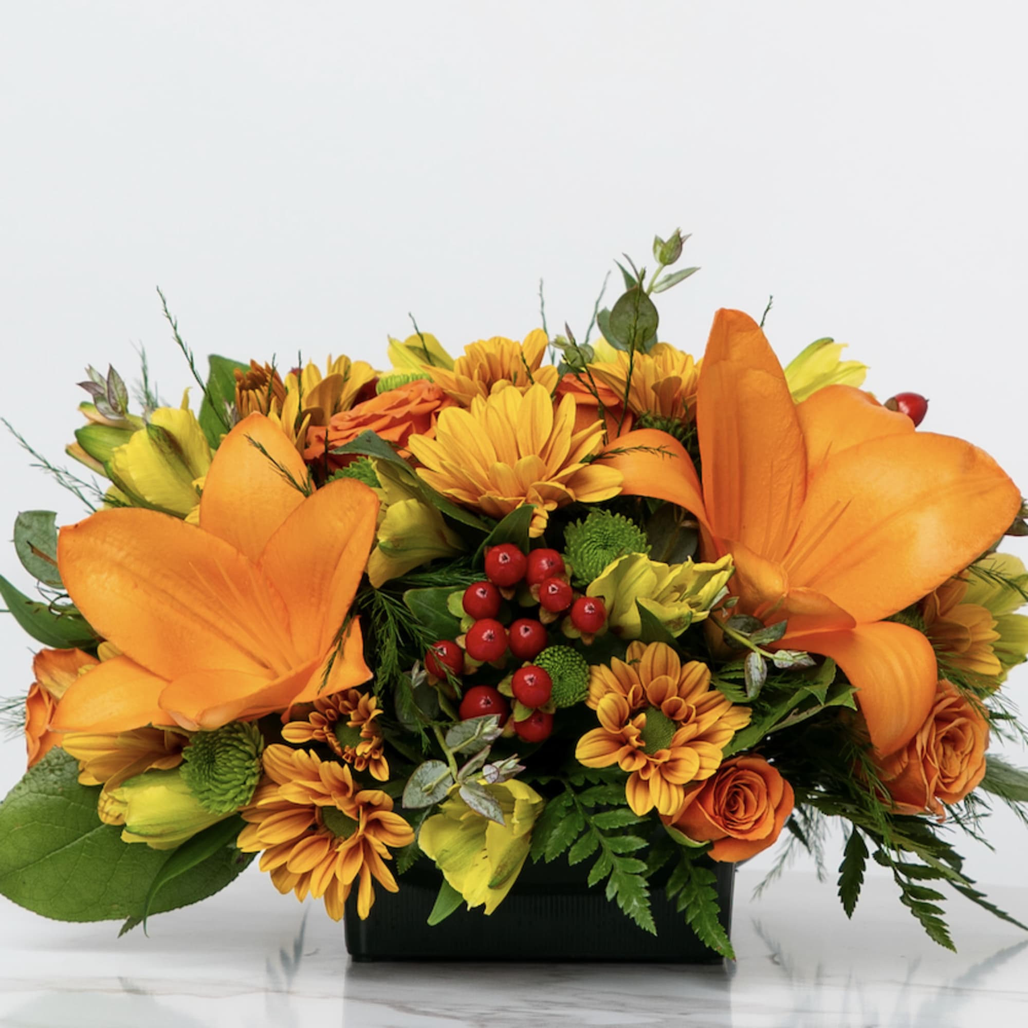 Orange and yellow floral arrangement in a black container