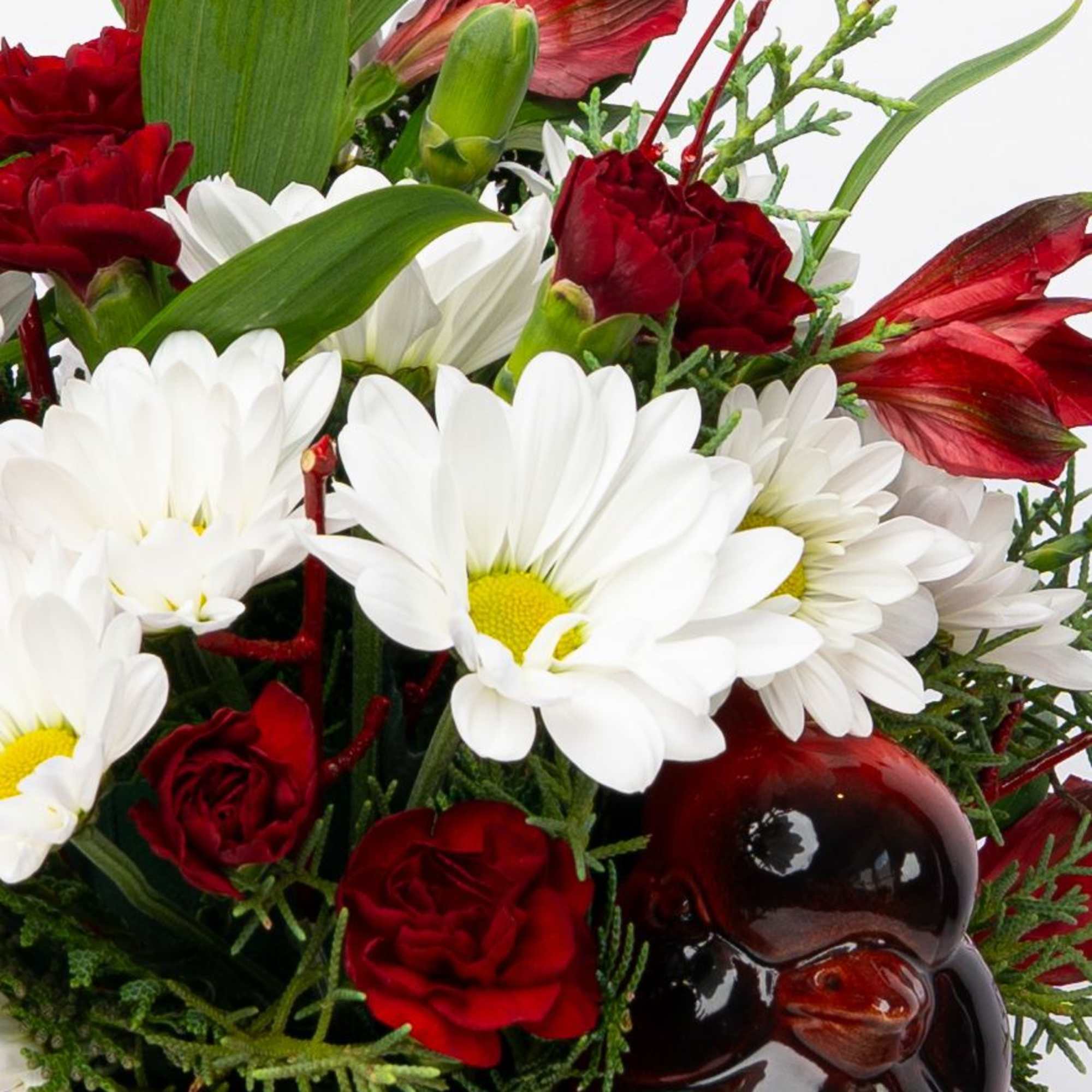 Red and white flowers arranged with a glossy penguin figurine
