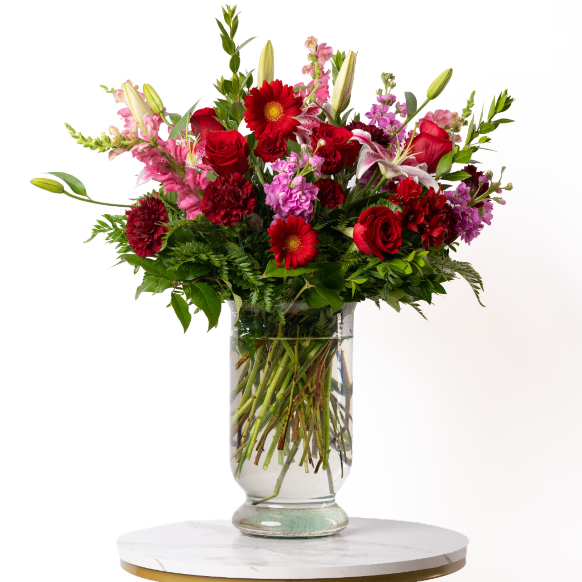 Mixed bouquet of red and pink flowers in a clear glass vase