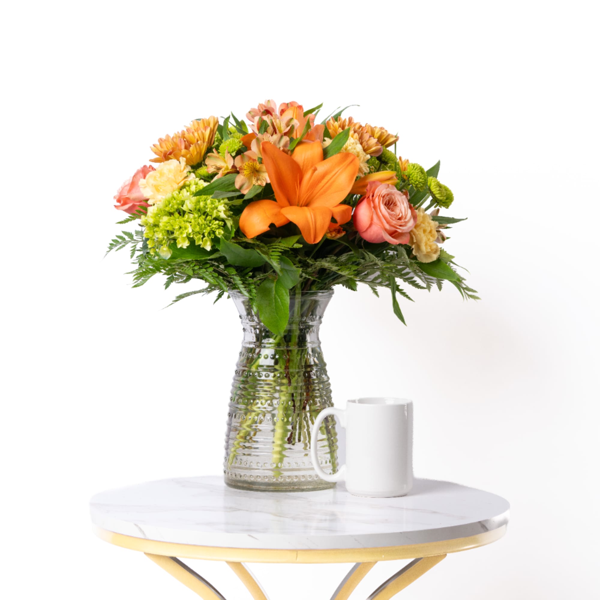 Orange and pink mixed bouquet in a clear glass vase on a table, photo 2 of 2