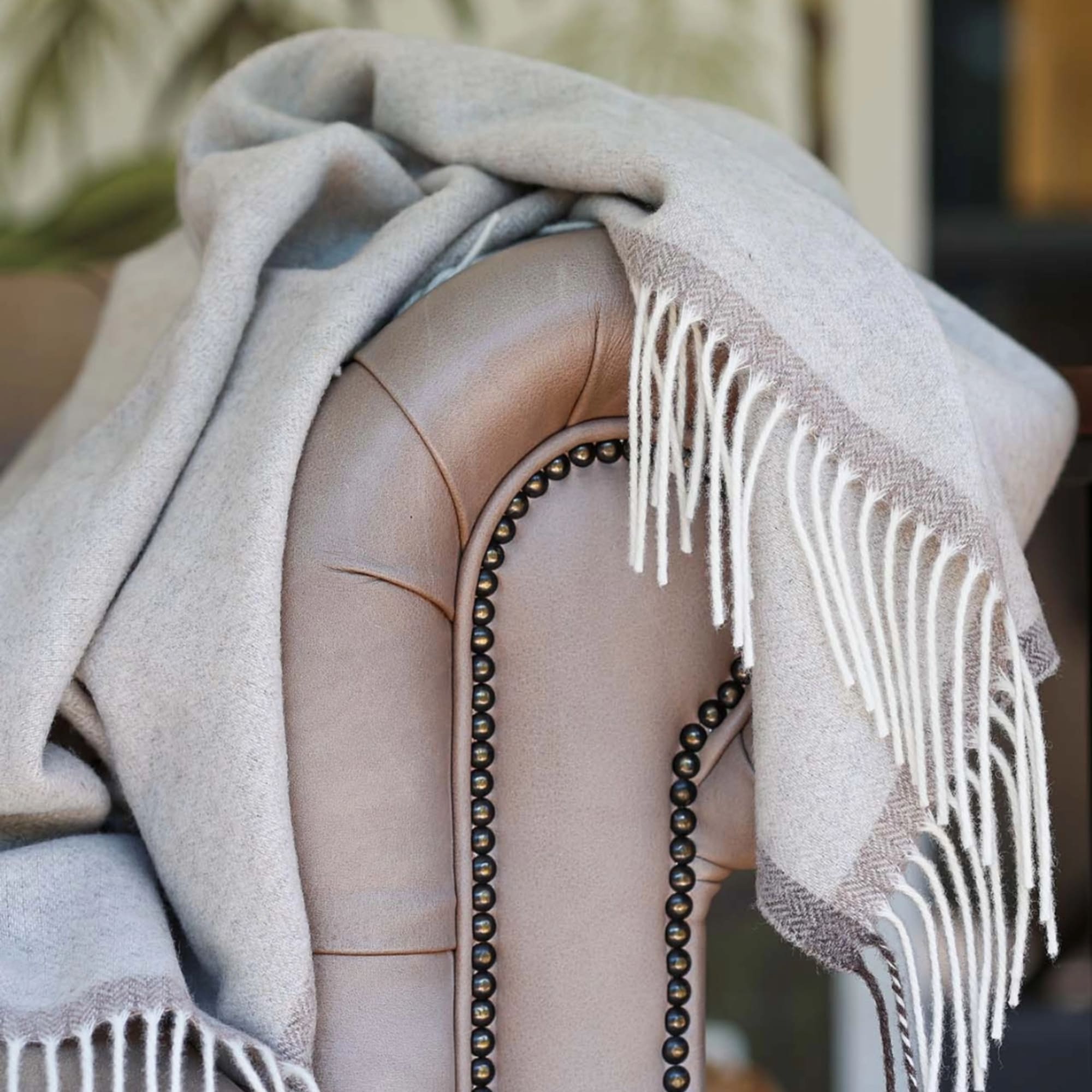 A light gray throw blanket draped over a beige upholstered chair
