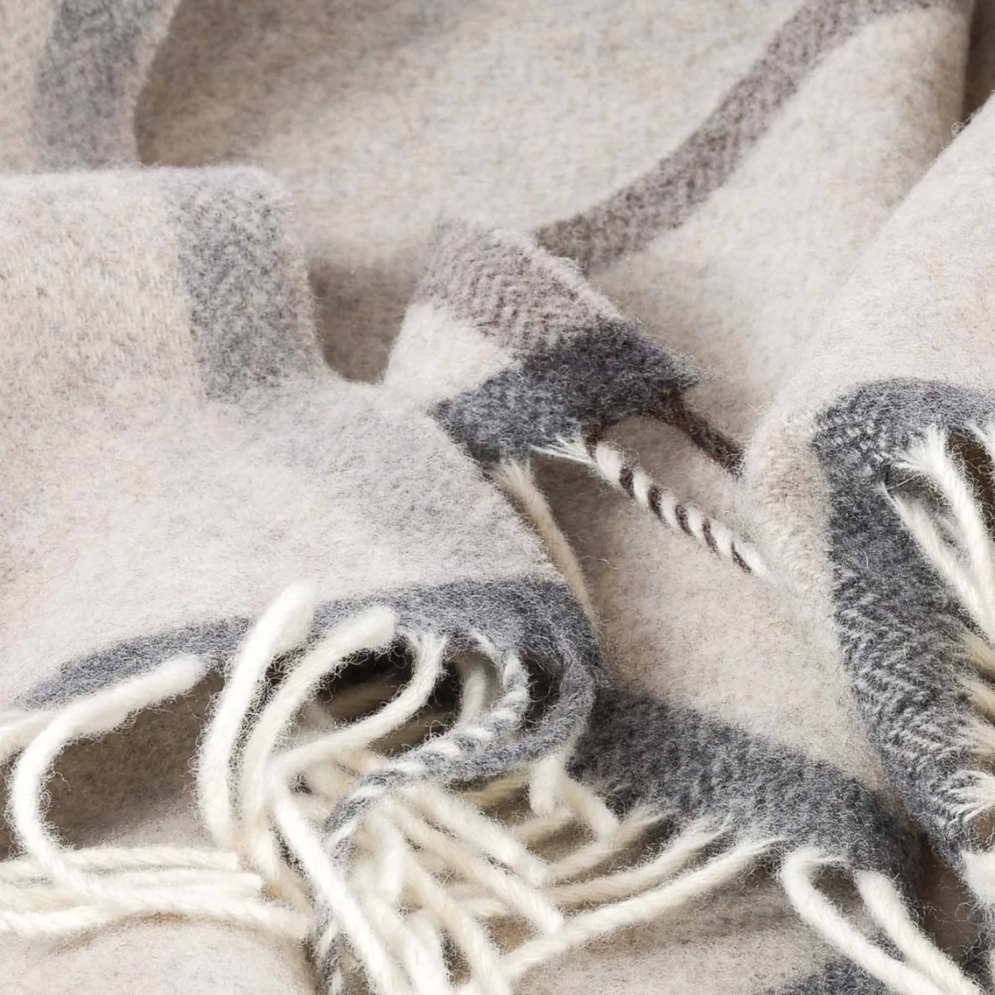 Close-up of a gray and white fuzzy woven blanket with fringe