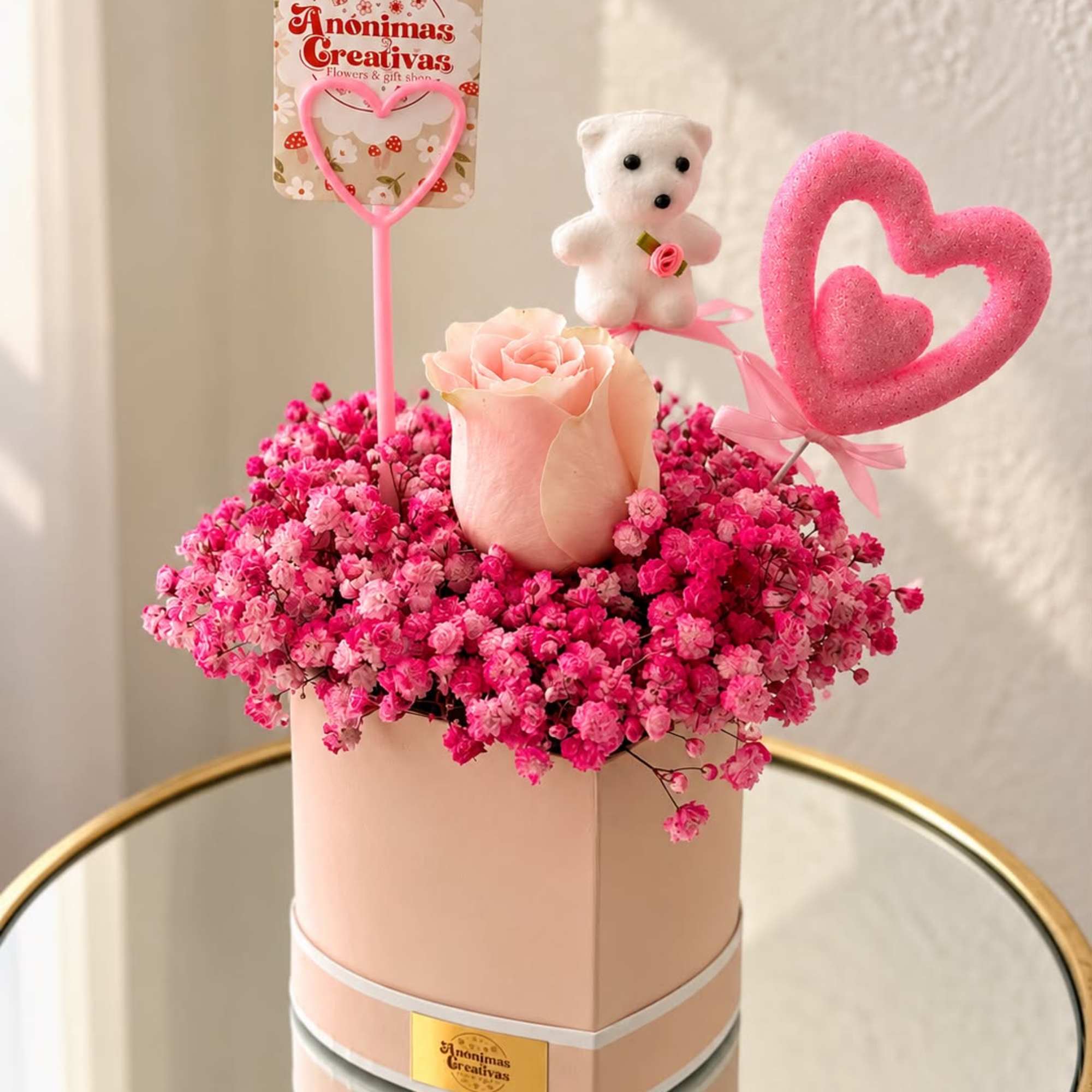 Pink rose arrangement in a round box with a teddy bear and heart toppers
