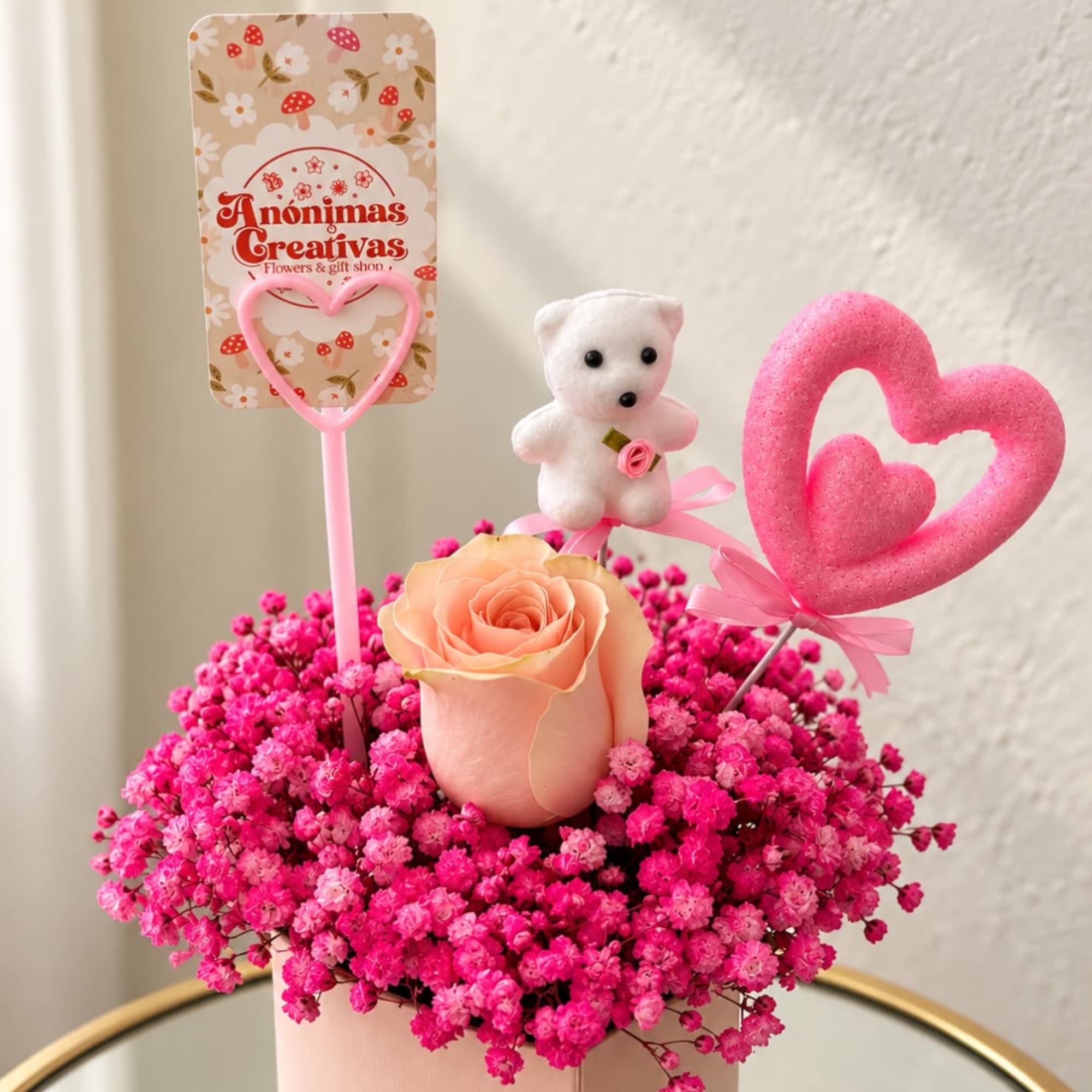 Pink rose arrangement with baby’s breath, a teddy bear, and heart toppers