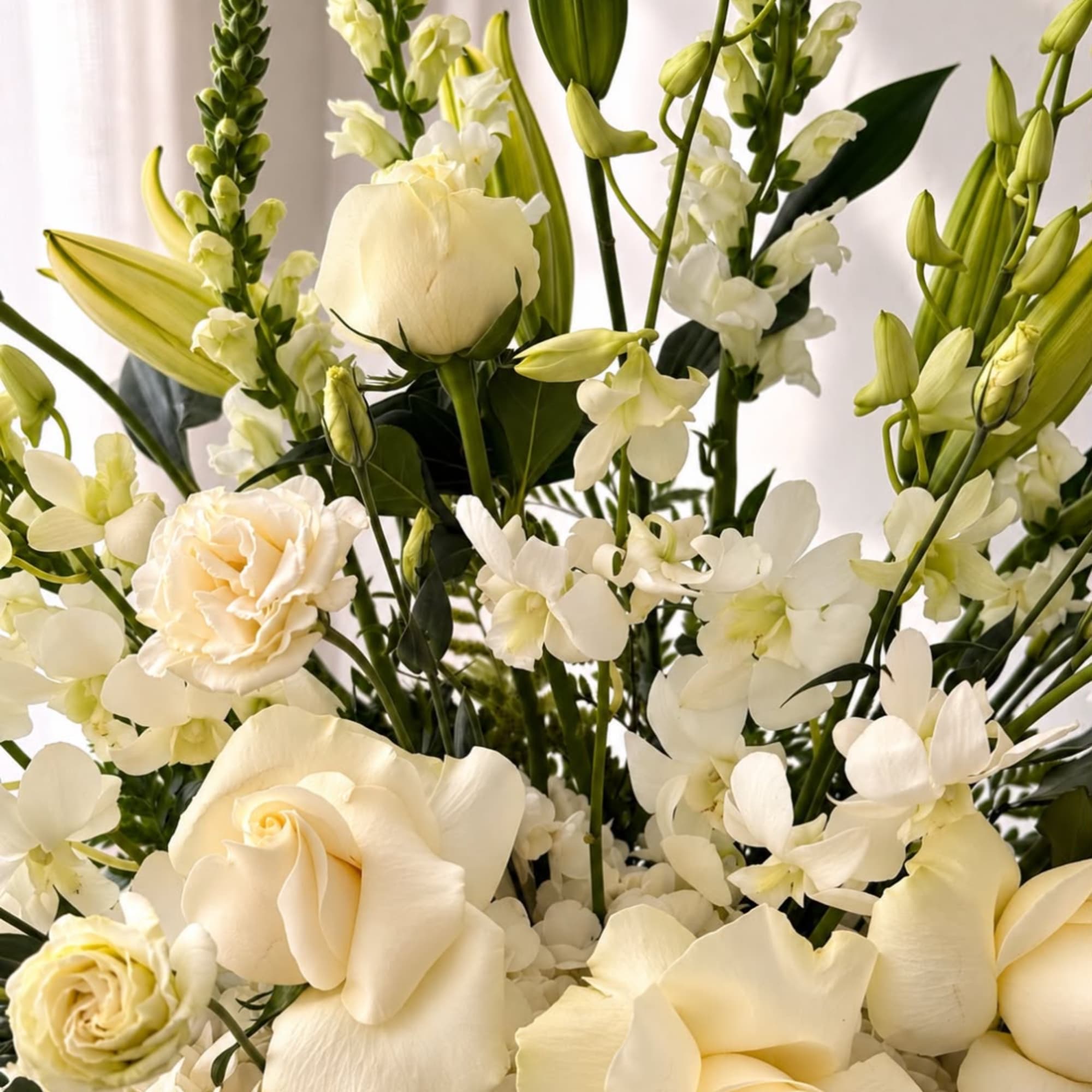 Cream roses and white lilies in a soft, upright bouquet