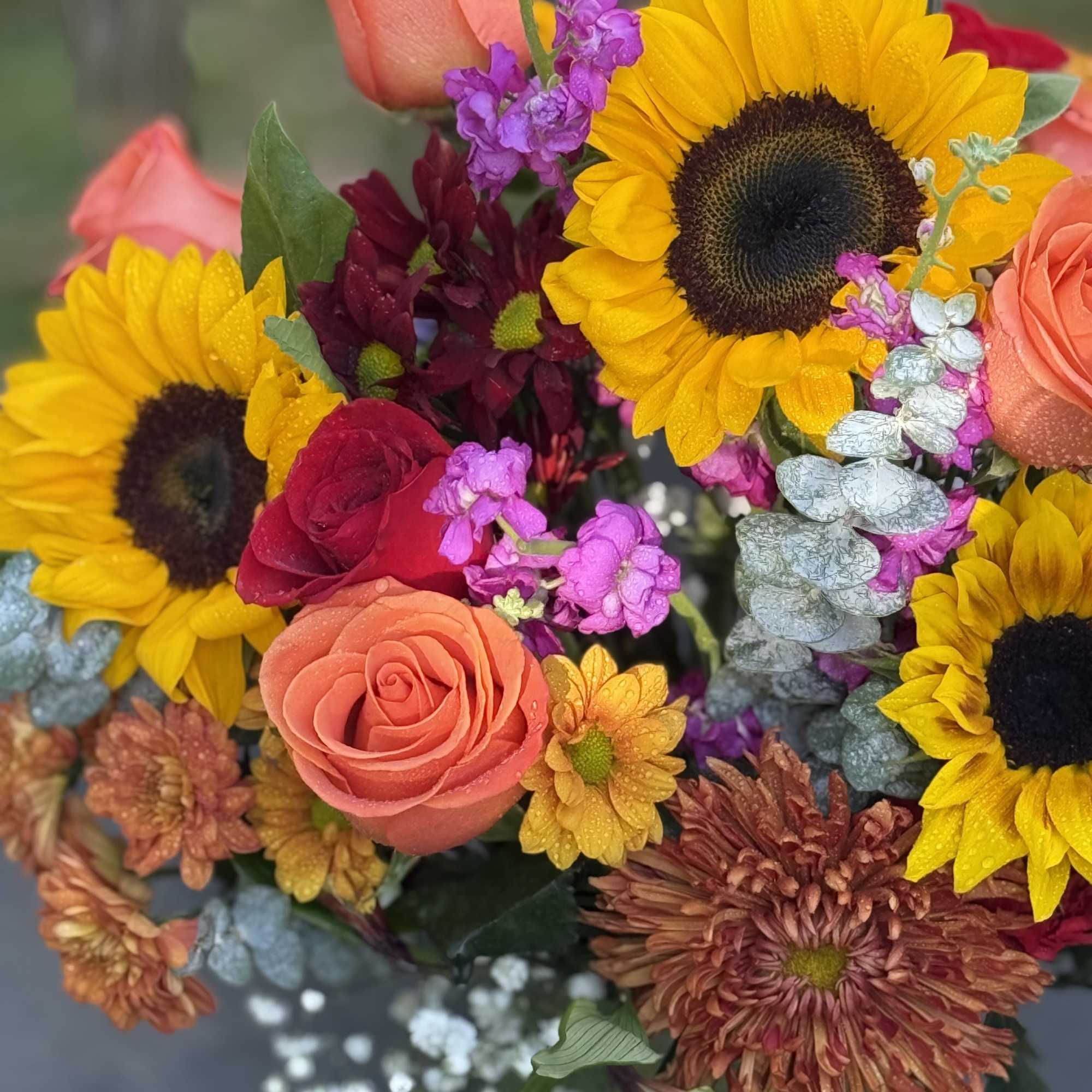Bouquet of sunflowers, roses, and purple filler flowers