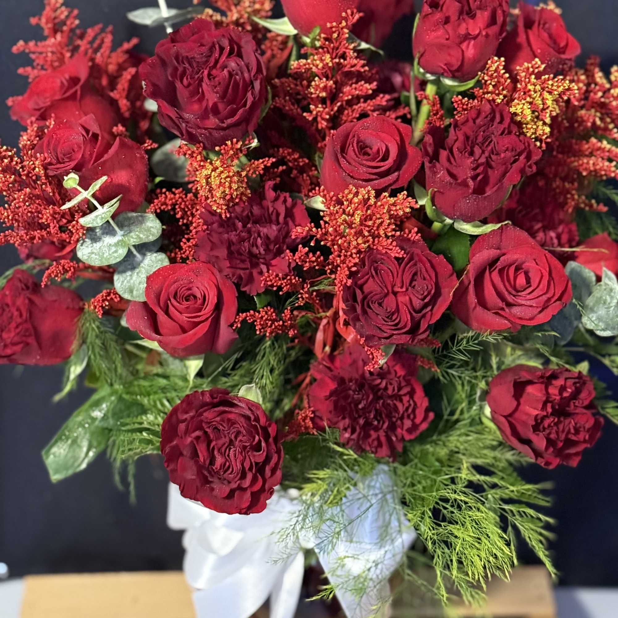 Bouquet of red roses and burgundy blooms in a vase