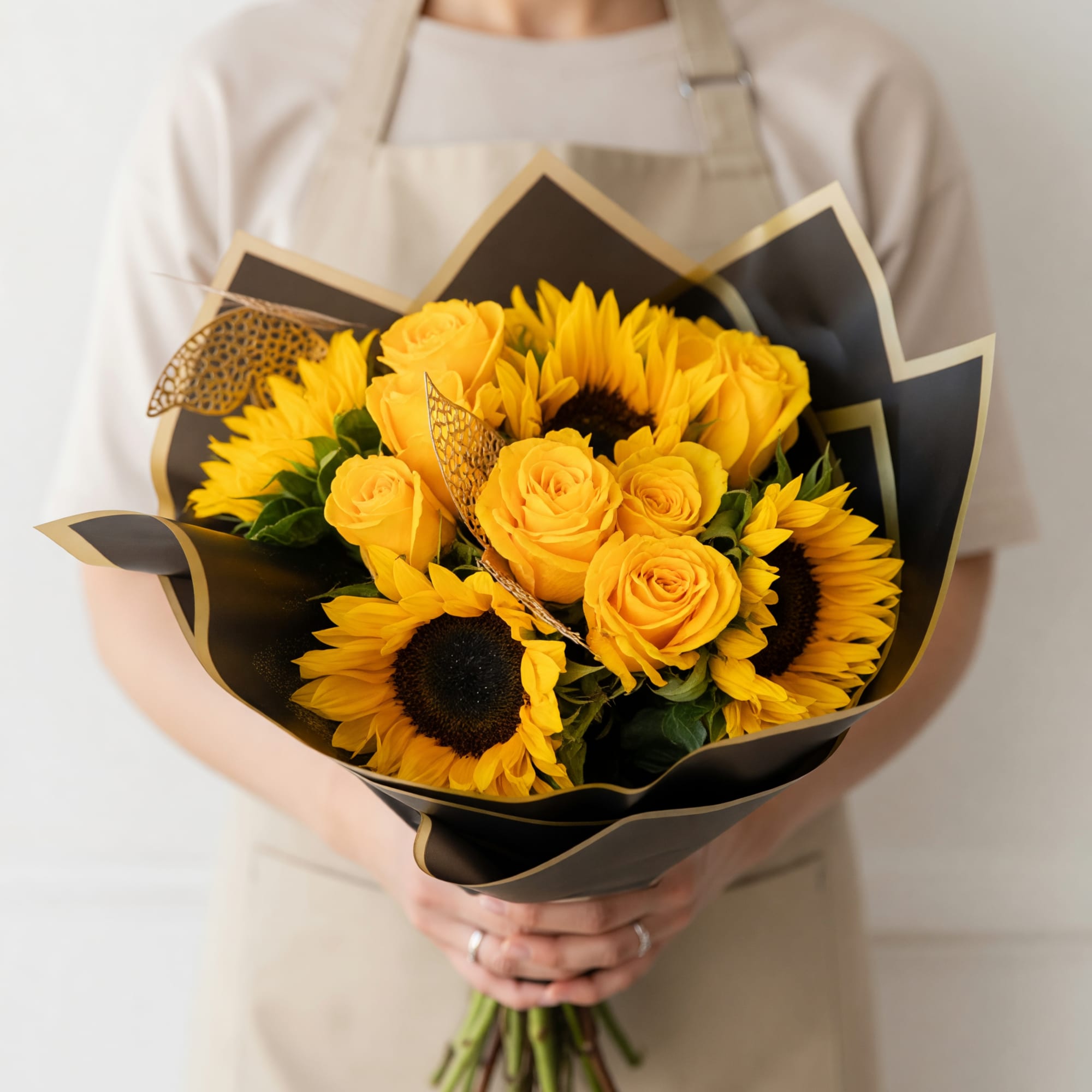 Bright yellow roses paired with cheerful sunflowers give this hand-tied flower arrangement