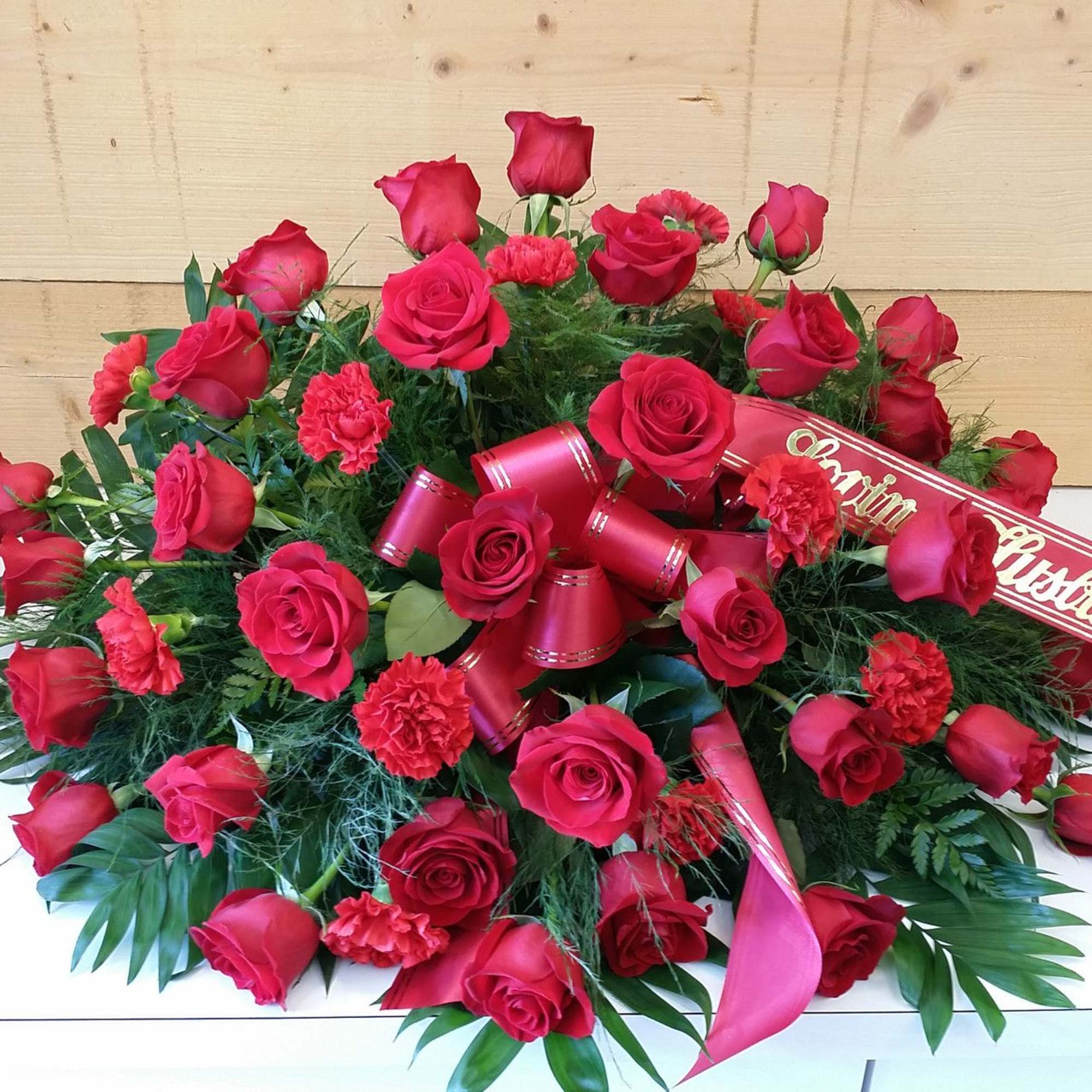Red rose and carnation arrangement with ribbon accents