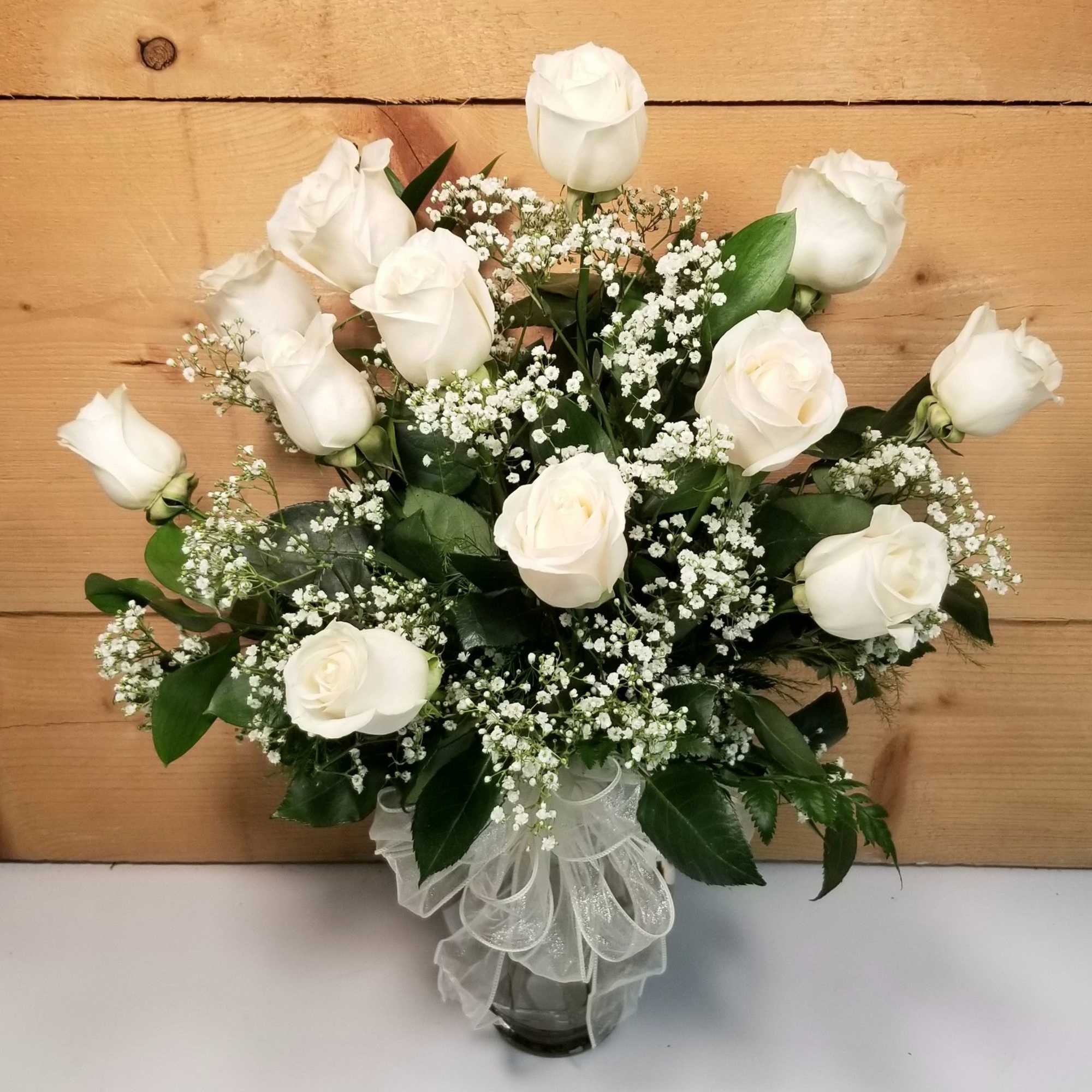 White roses arranged in a glass vase with baby's breath