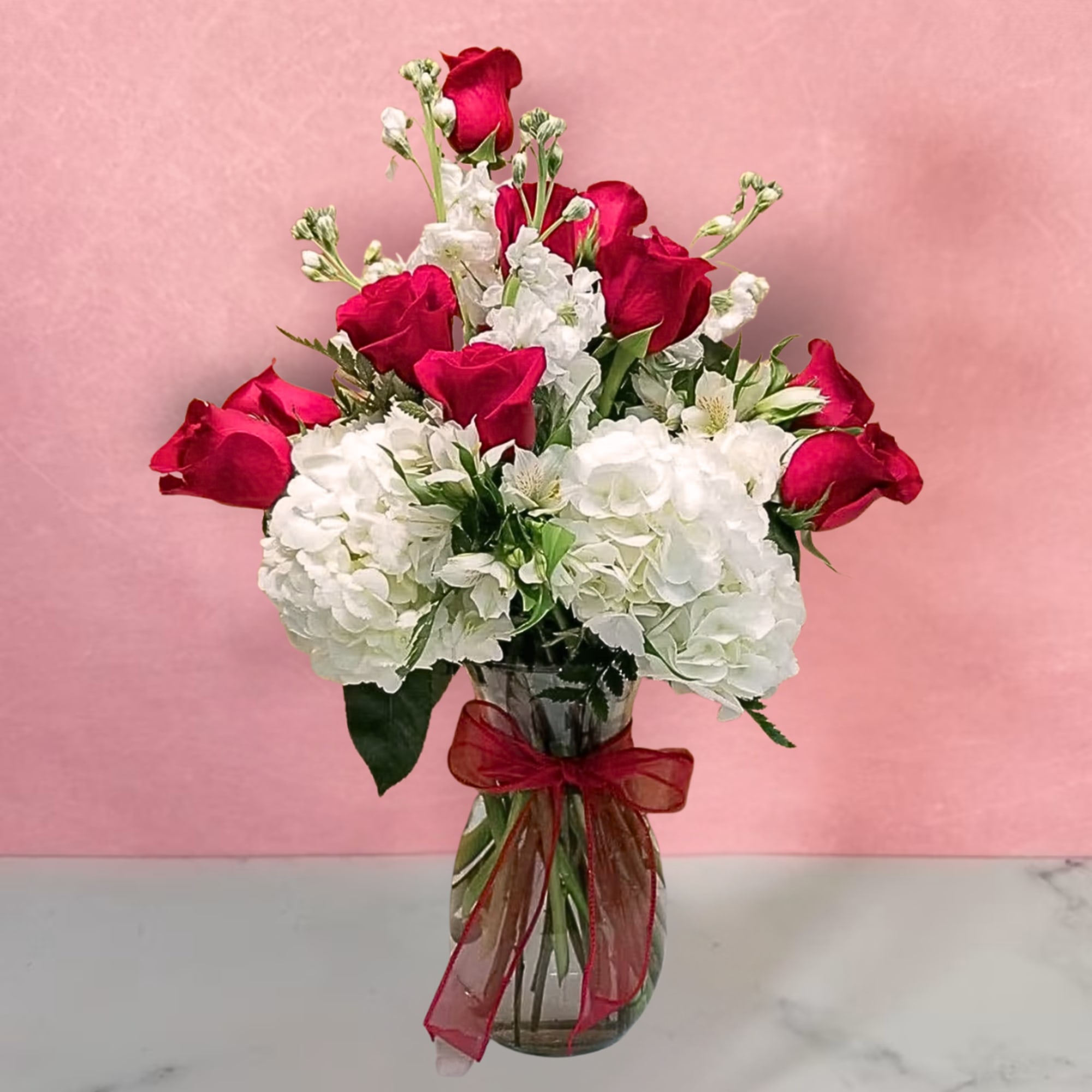 Bouquet of red roses and white hydrangeas in a glass vase with a red ribbon
