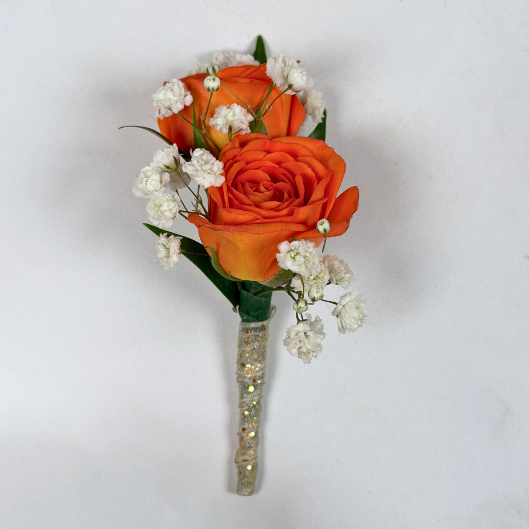 Two vivid orange rose blooms make this boutonniere a bright, celebratory accent