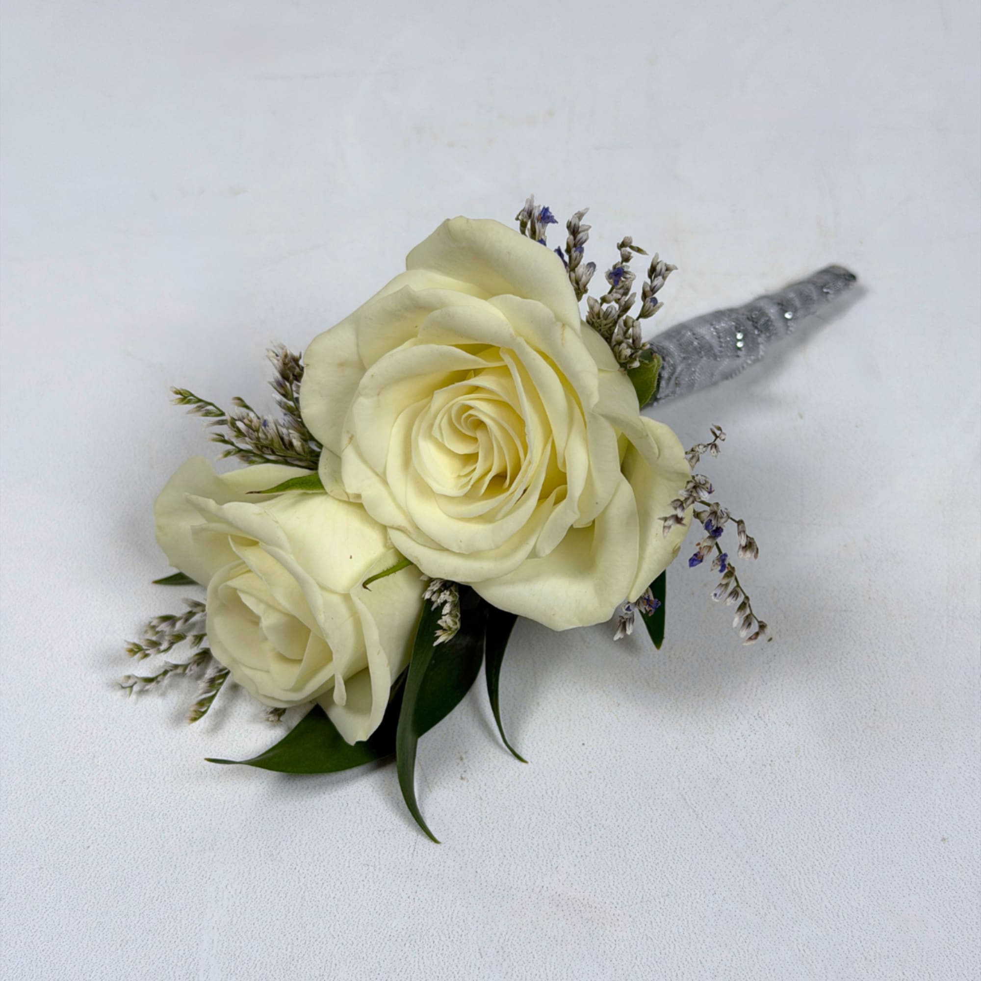 Two creamy ivory roses are center stage in our Opal Boutonniere, a, photo 2 of 3