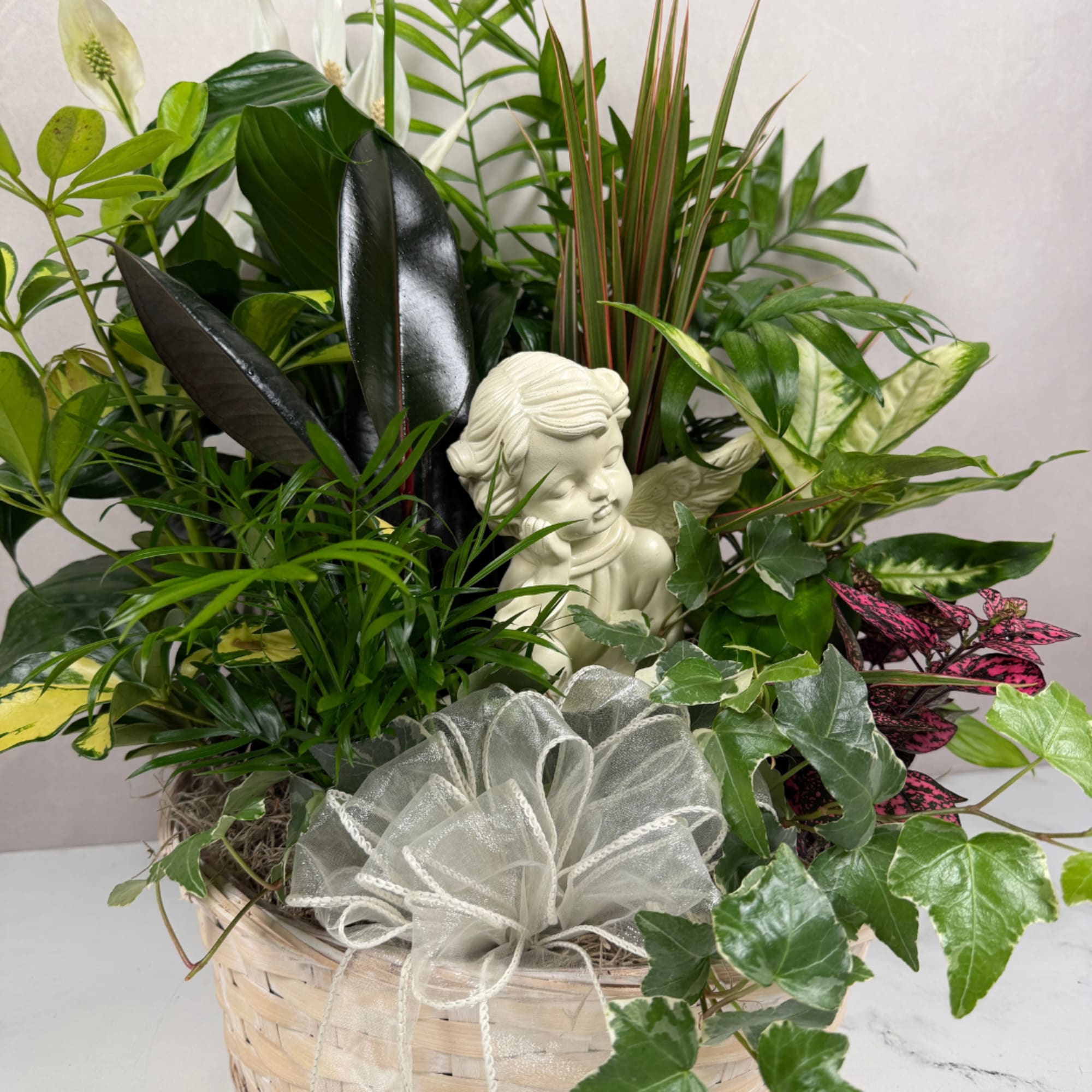 Mixed green plant basket with a small angel figurine and sheer bow