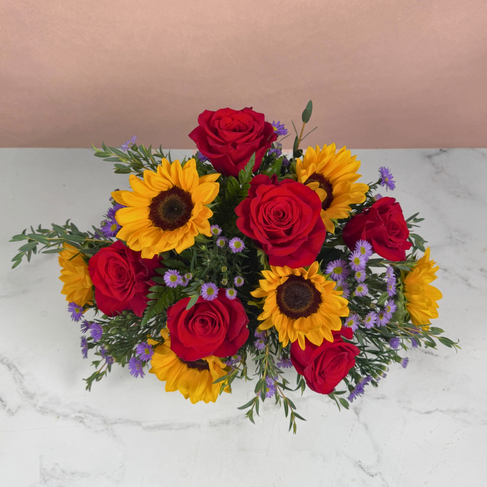 Bouquet of red roses and yellow sunflowers with small purple flowers