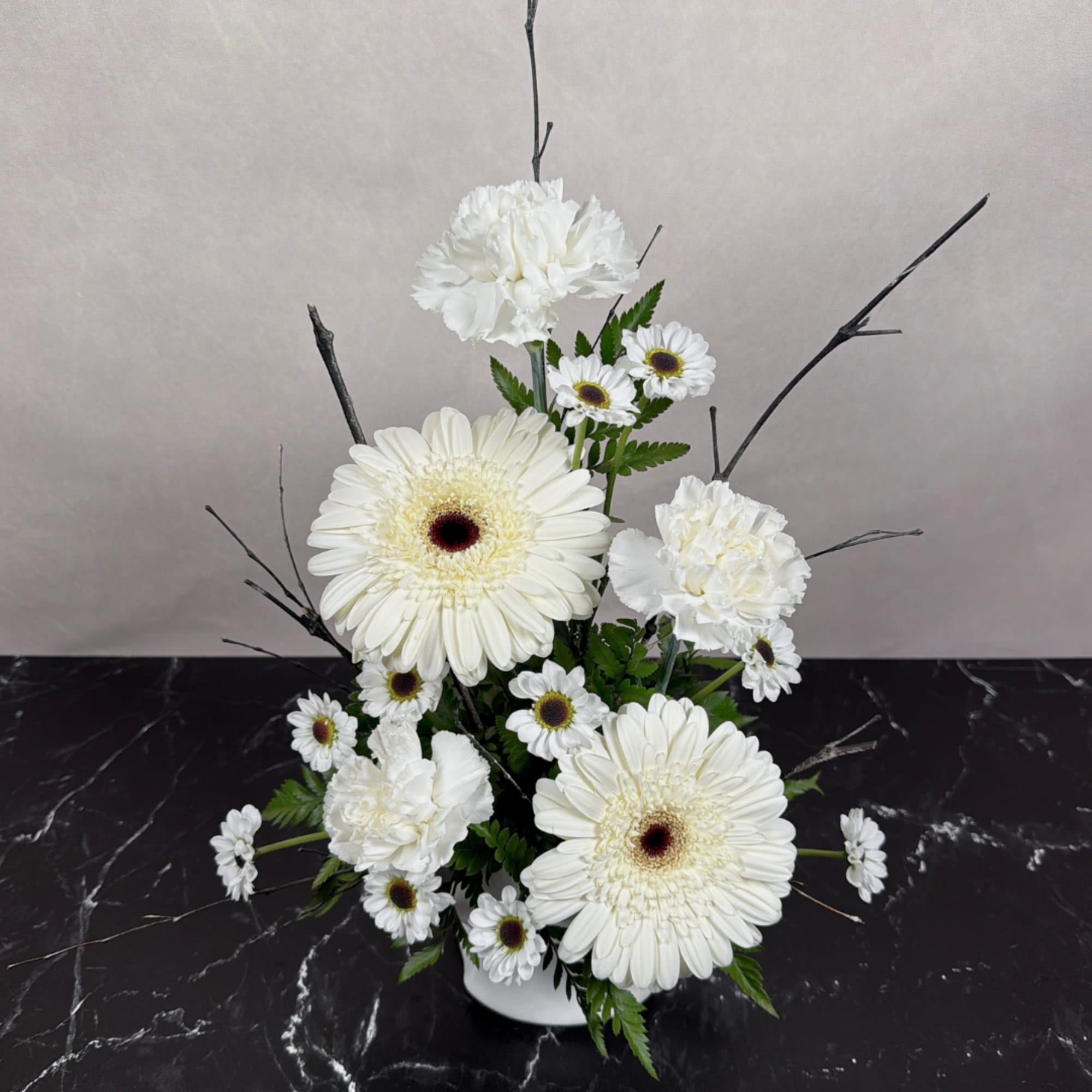 White gerbera daisies and carnations in a white vase