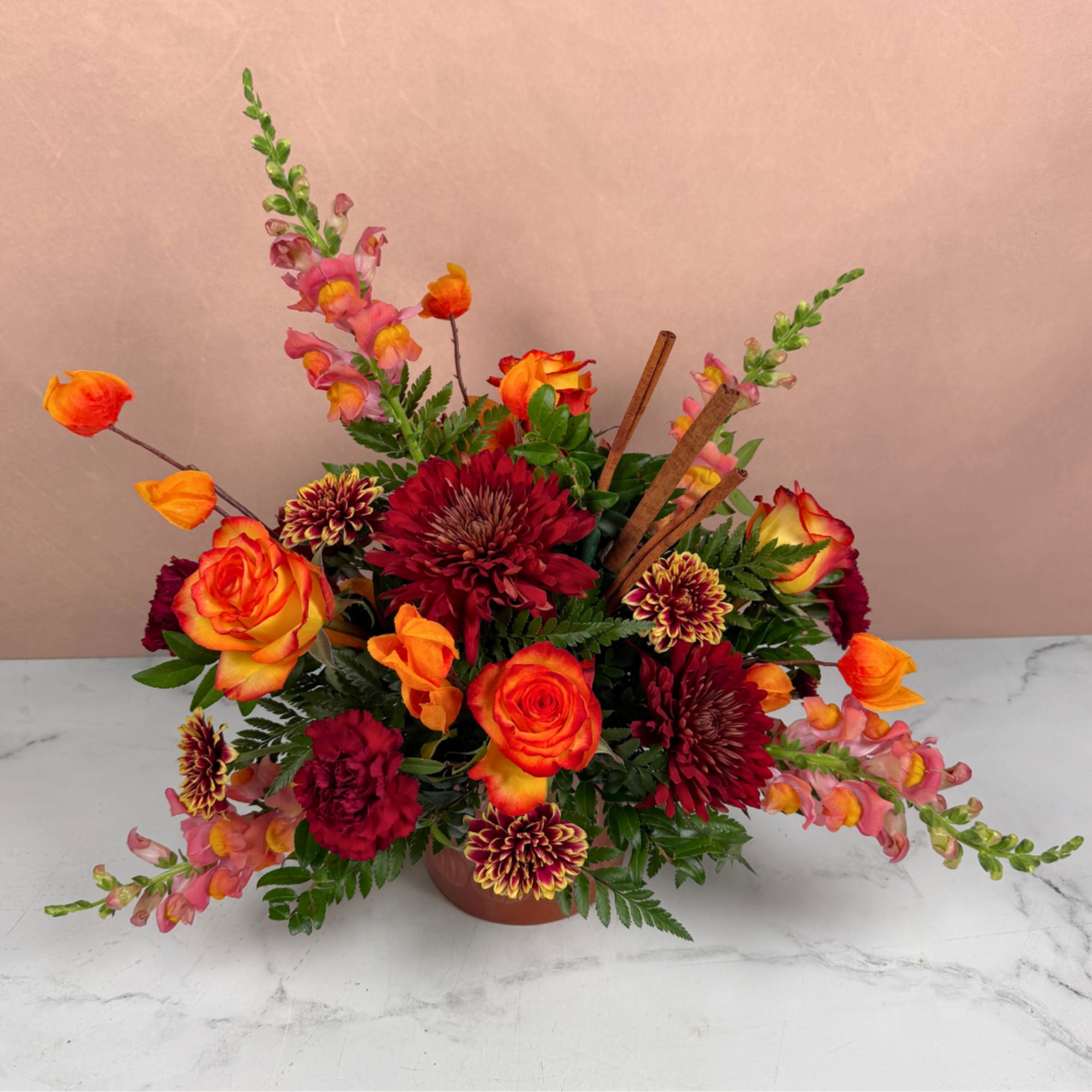 Orange and red mixed flower arrangement in a low vase