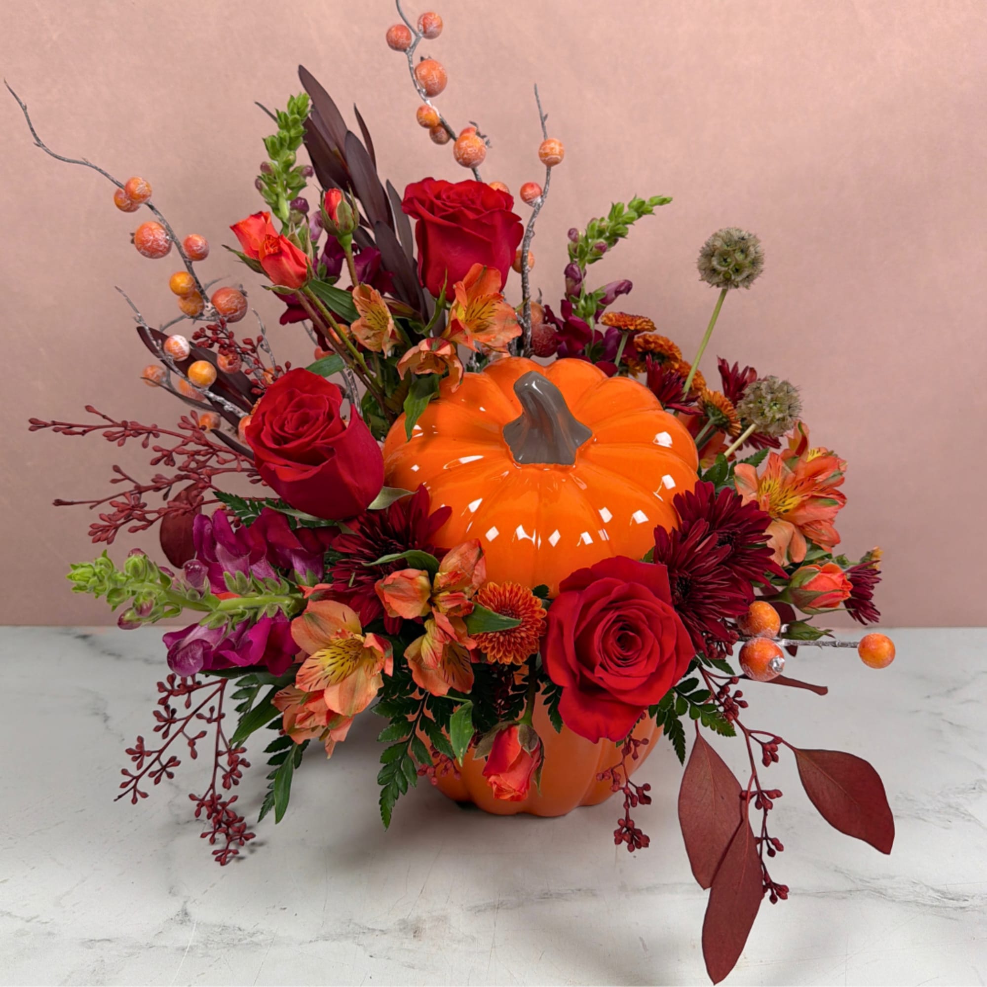 Fall floral arrangement around an orange pumpkin centerpiece