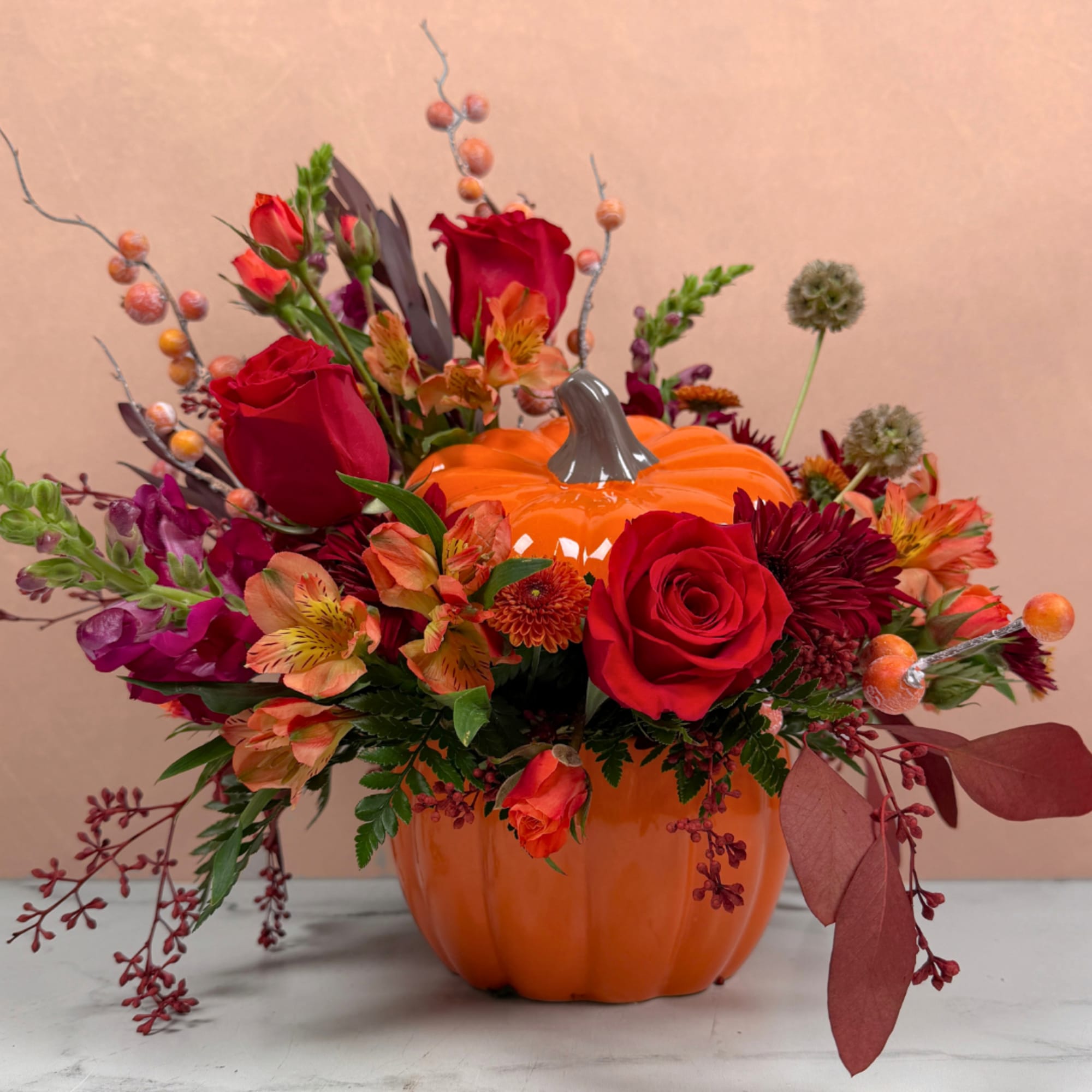 Pumpkin-shaped vase filled with red and orange flowers