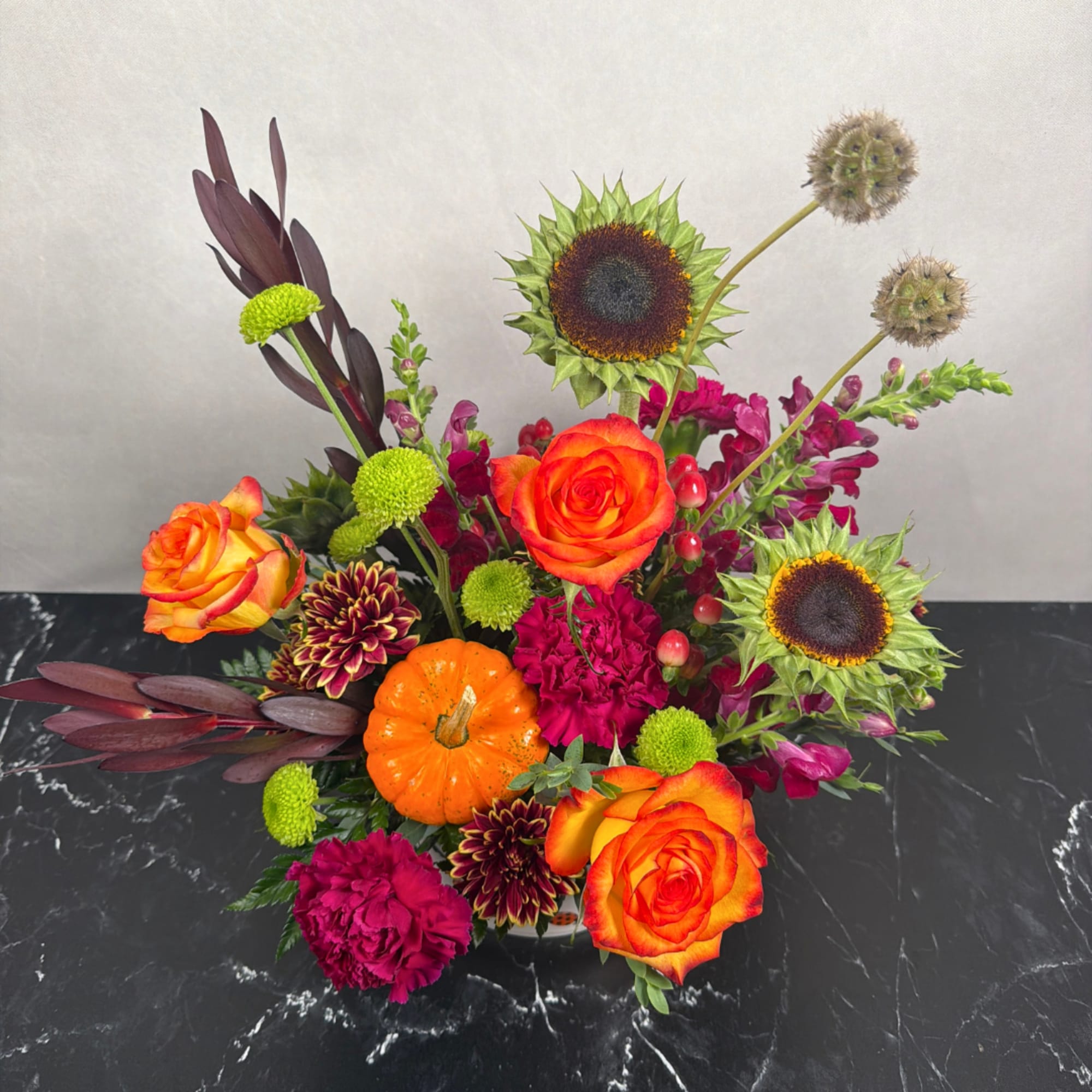 Mixed bouquet with orange roses, sunflowers, and magenta blooms in a vase