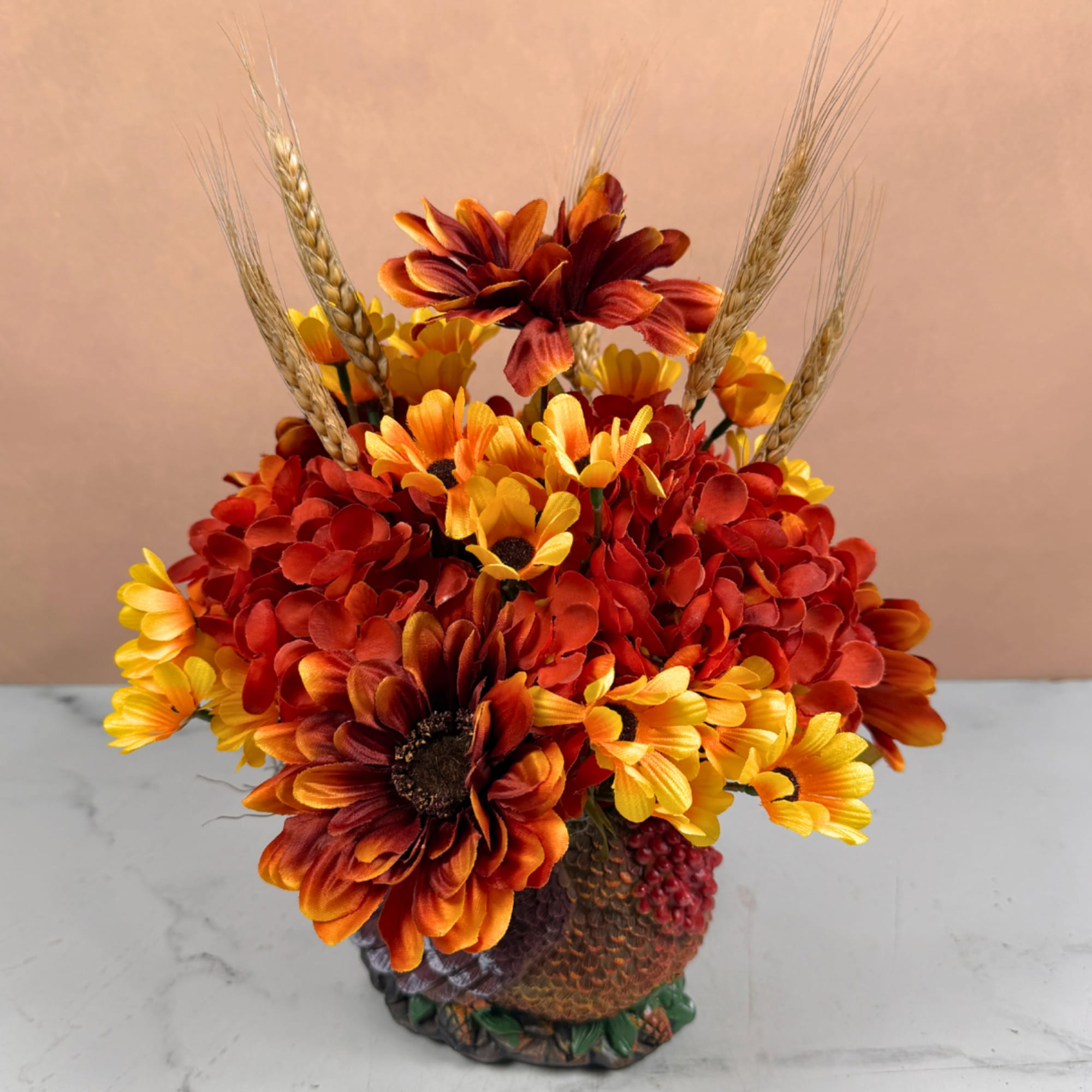 Autumn bouquet of orange and yellow flowers in a textured vase with wheat stems