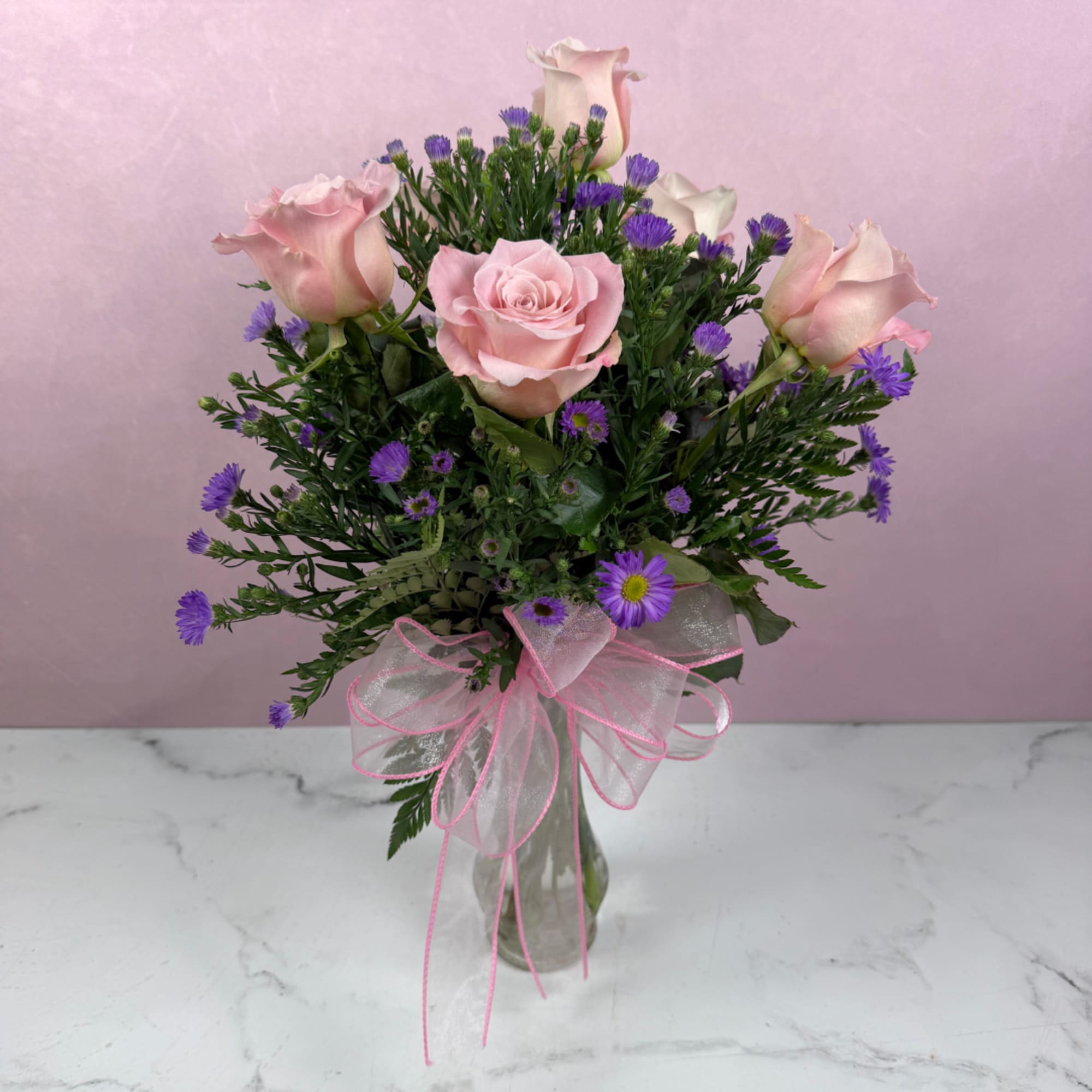 Pink roses and purple daisies in a clear glass vase with a pink ribbon bow., photo 3 of 4