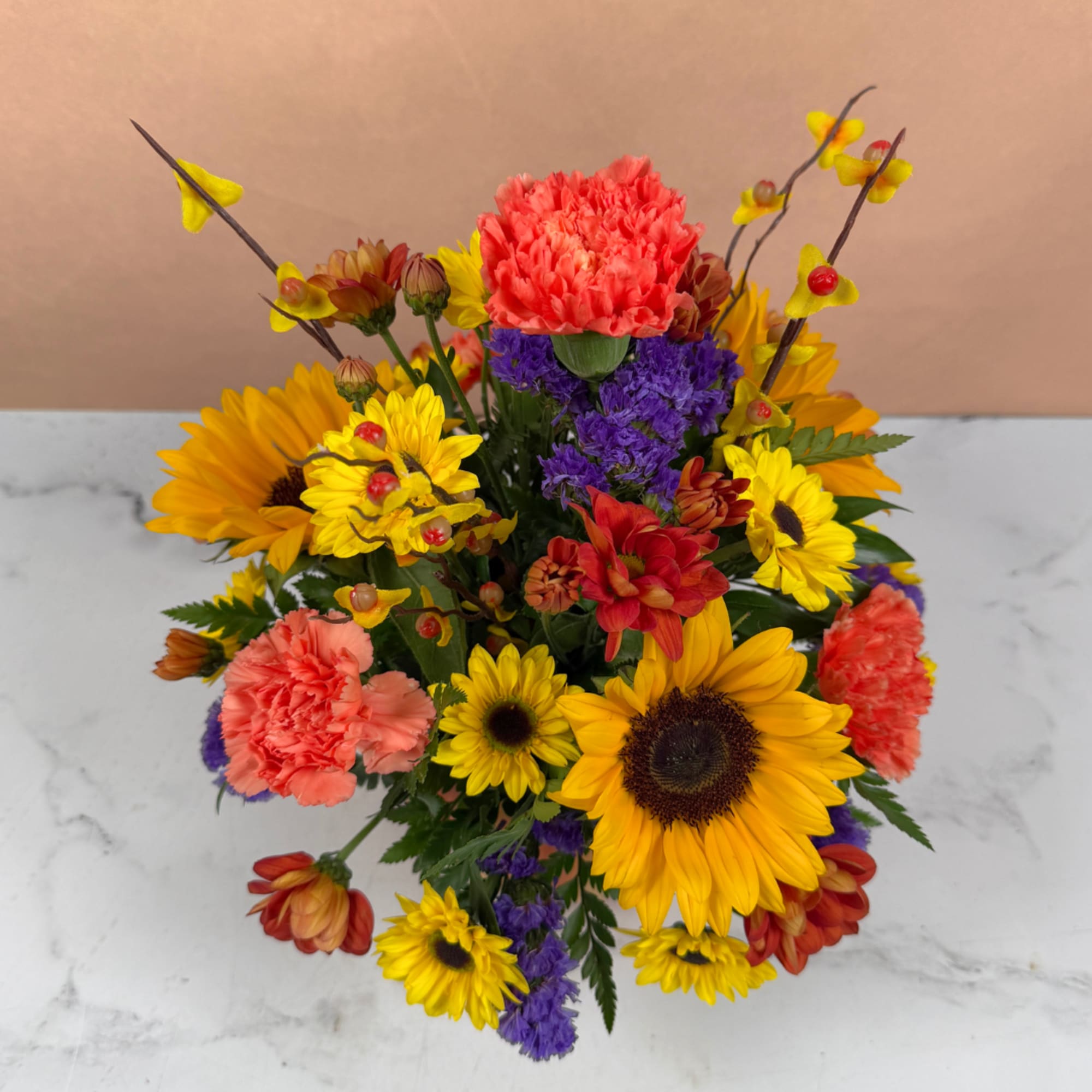 Bright mixed bouquet with sunflowers, carnations, and purple filler flowers