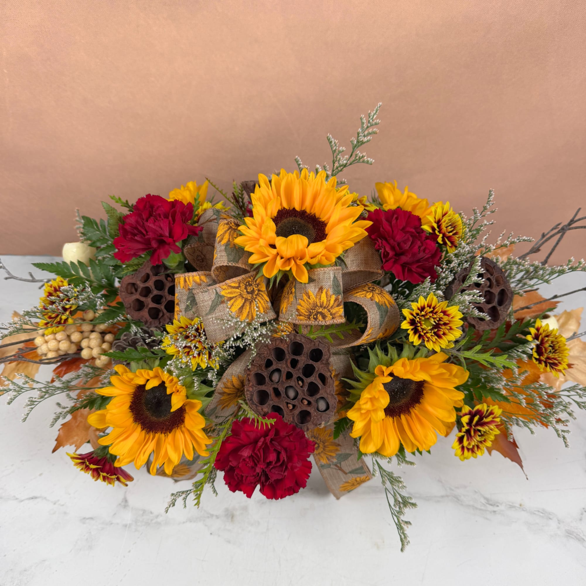 Sunflower and red carnation arrangement with burlap ribbon and lotus pods