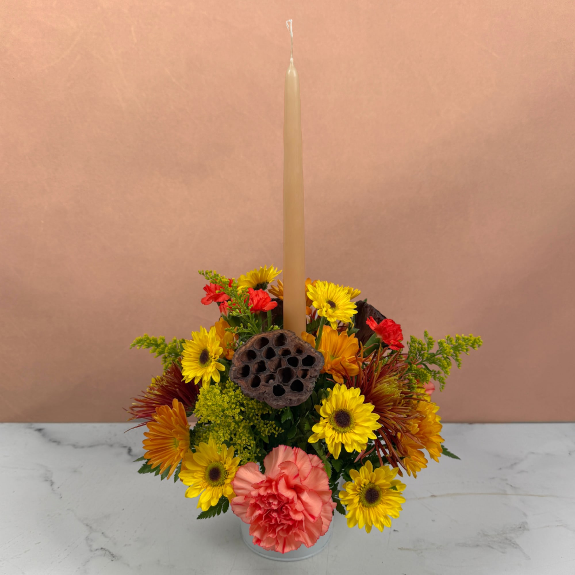 Colorful floral centerpiece with a tall taper candle in a glass vase