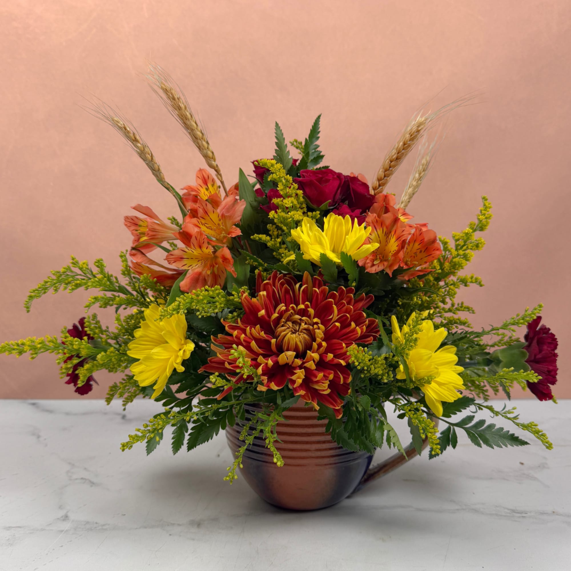 Mixed bouquet in a copper mug with red, yellow, and orange flowers