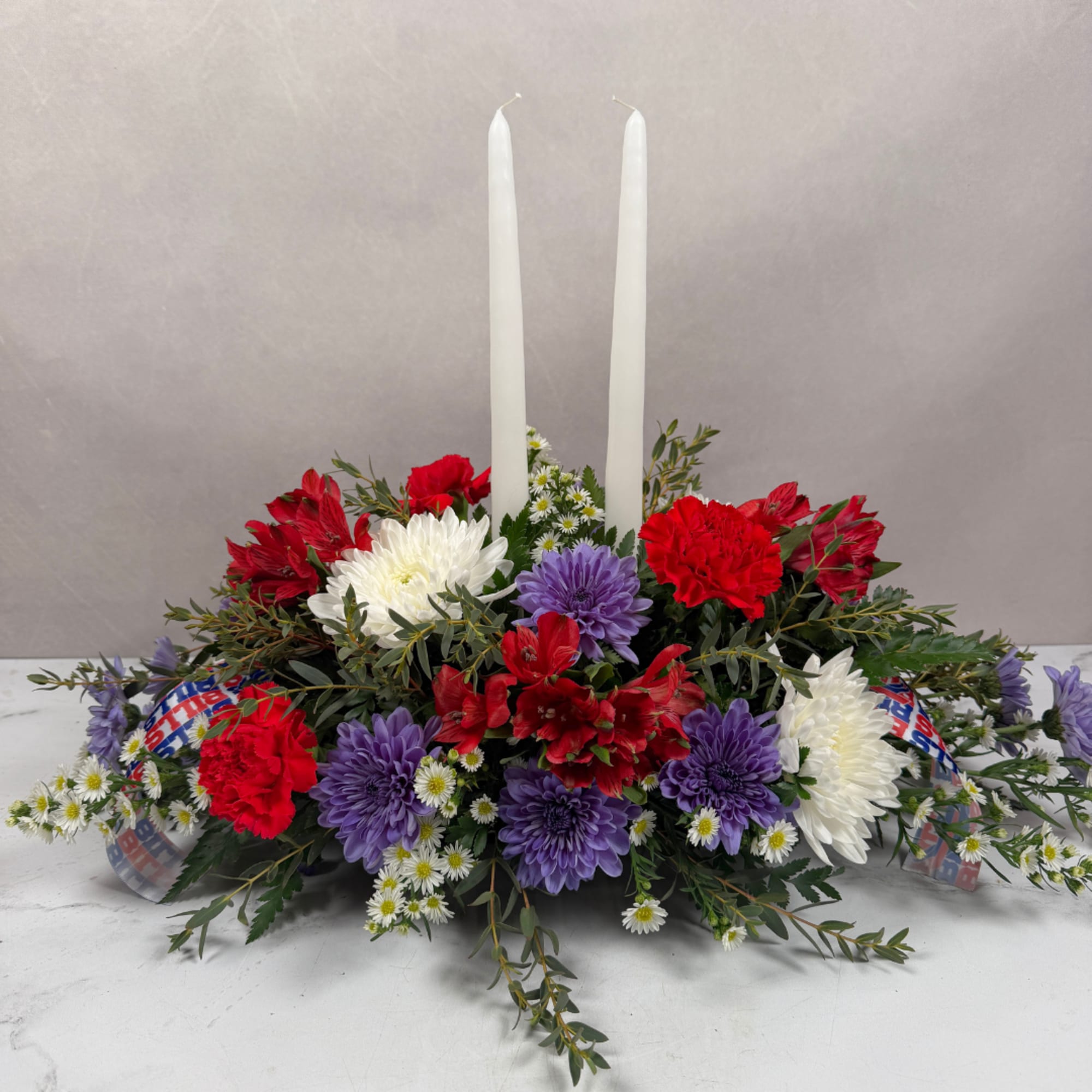 Red, white, and purple floral centerpiece with two white taper candles, photo 2 of 4