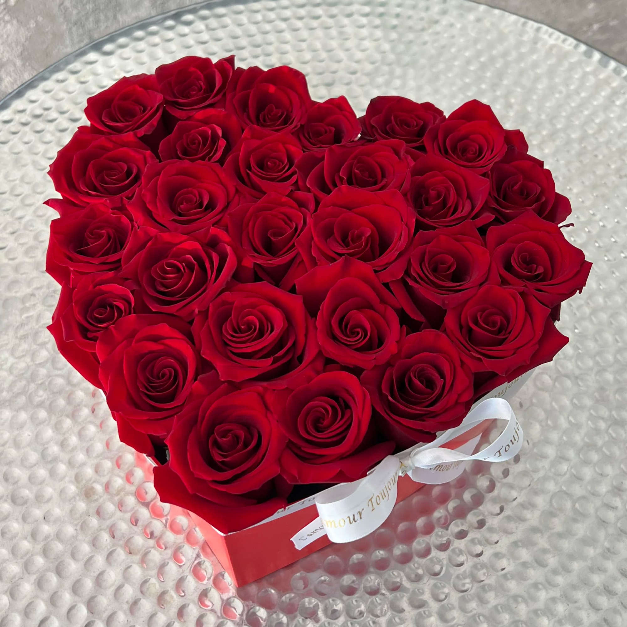 Heart-shaped box of red roses with a white ribbon