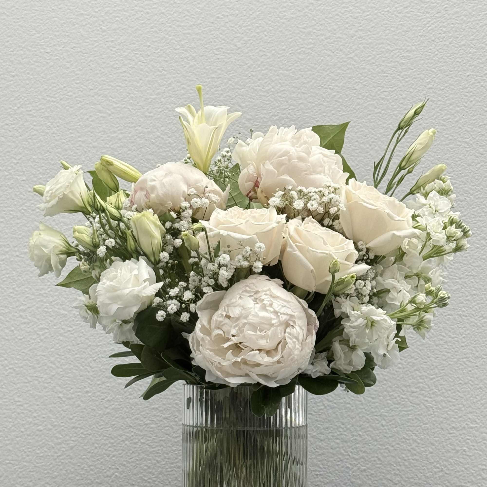 White arrangement filled with roses, stock flower, peony and lisianthus.  
