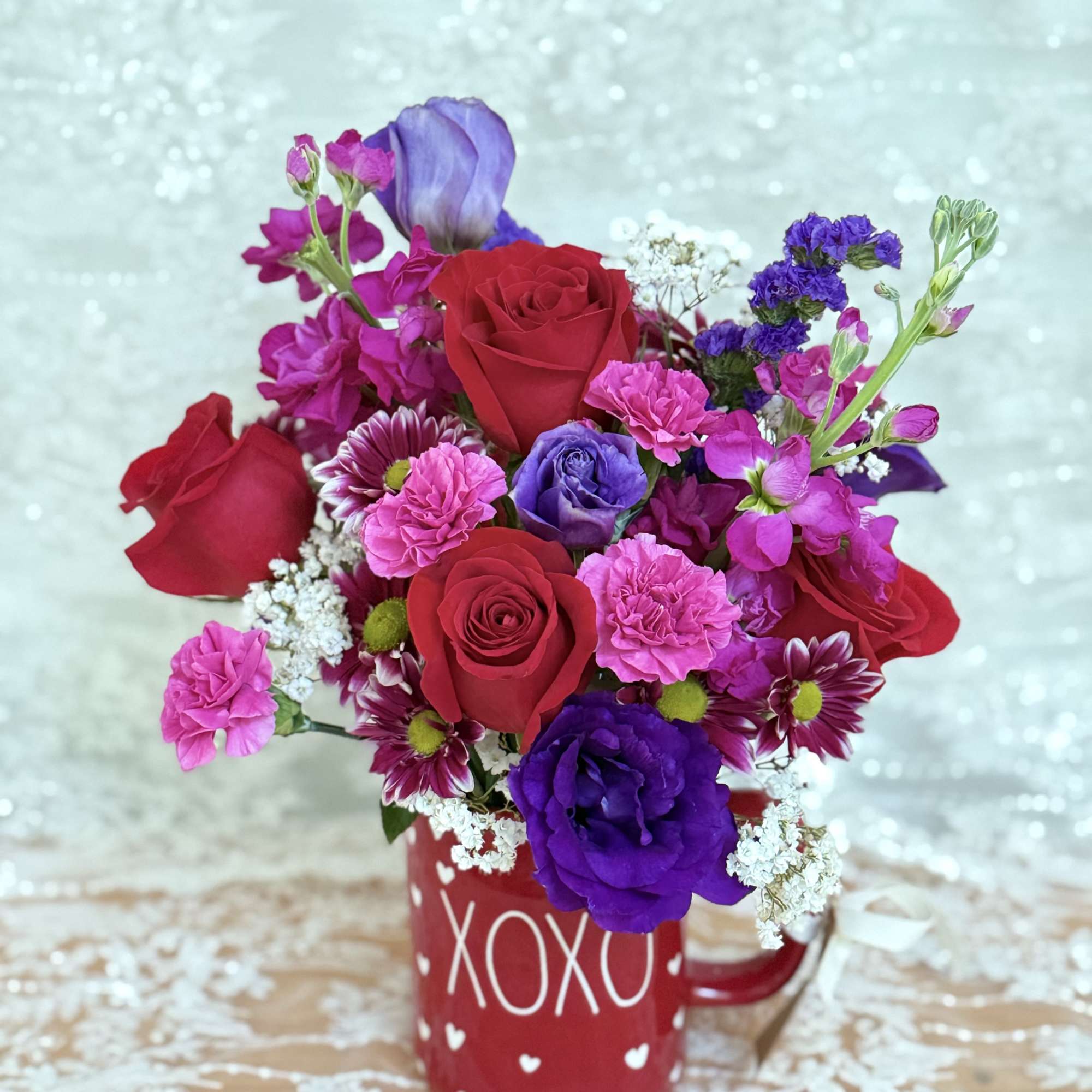 Coffee mug filled with roses, lisianthus, and spray mums.