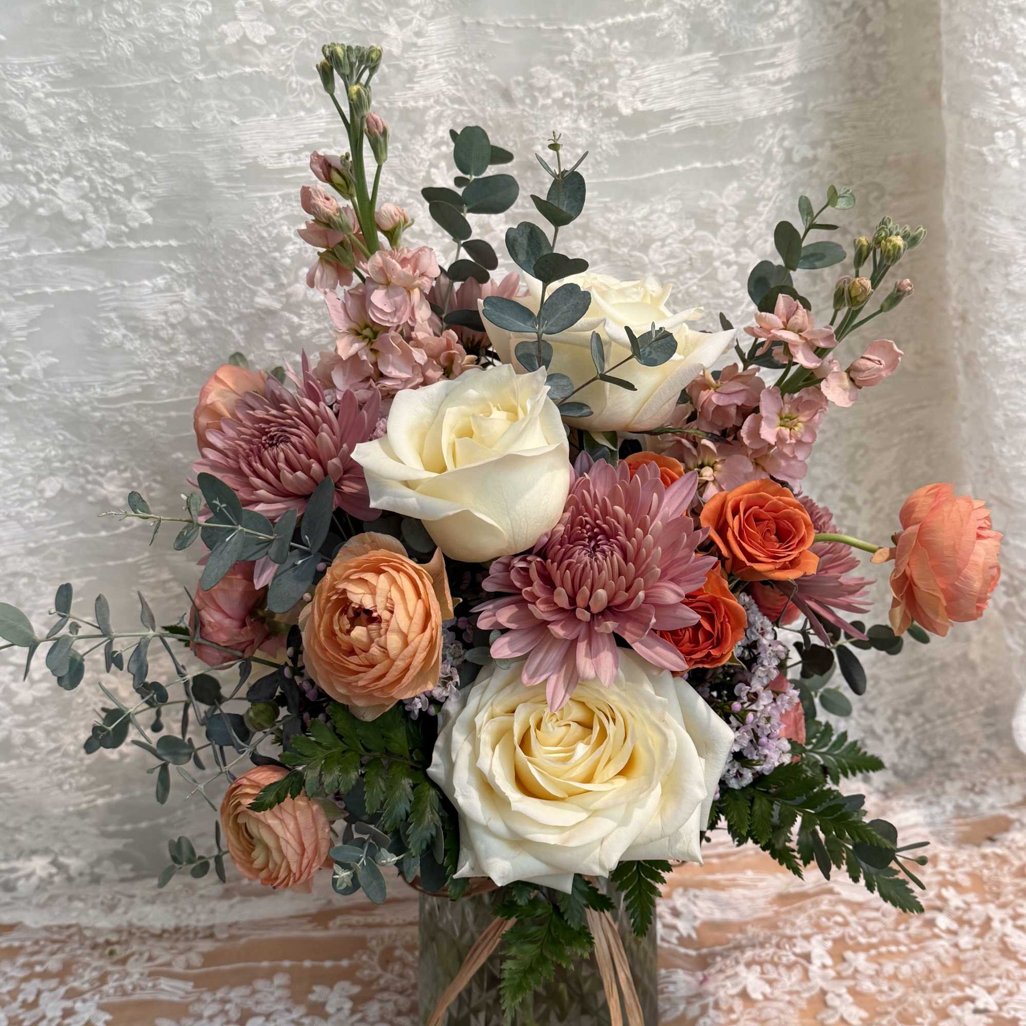Neutral color arrangement filled with cream roses, orange ranunculus, peach stock and