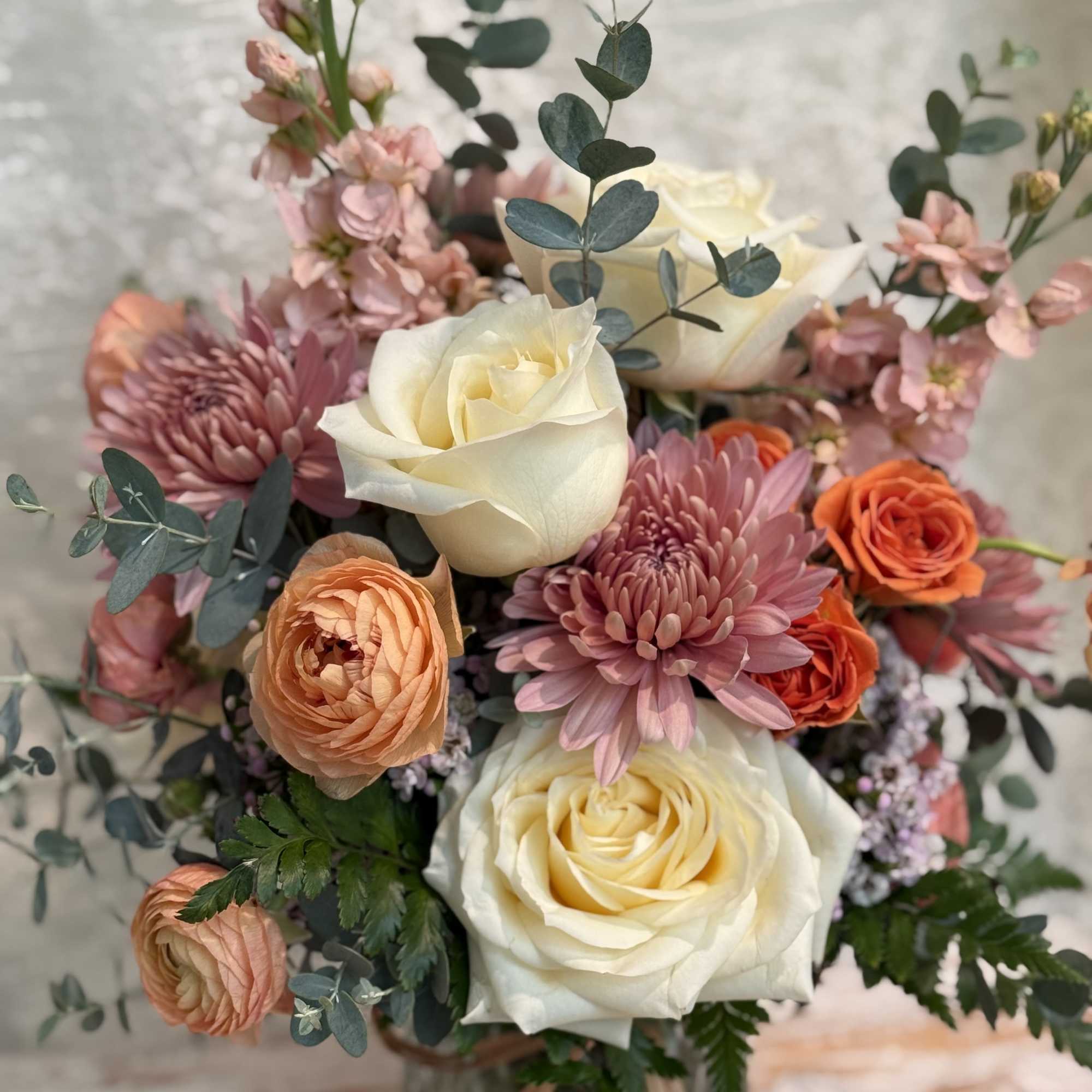Neutral color arrangement filled with cream roses, orange ranunculus, peach stock and, photo 2 of 2