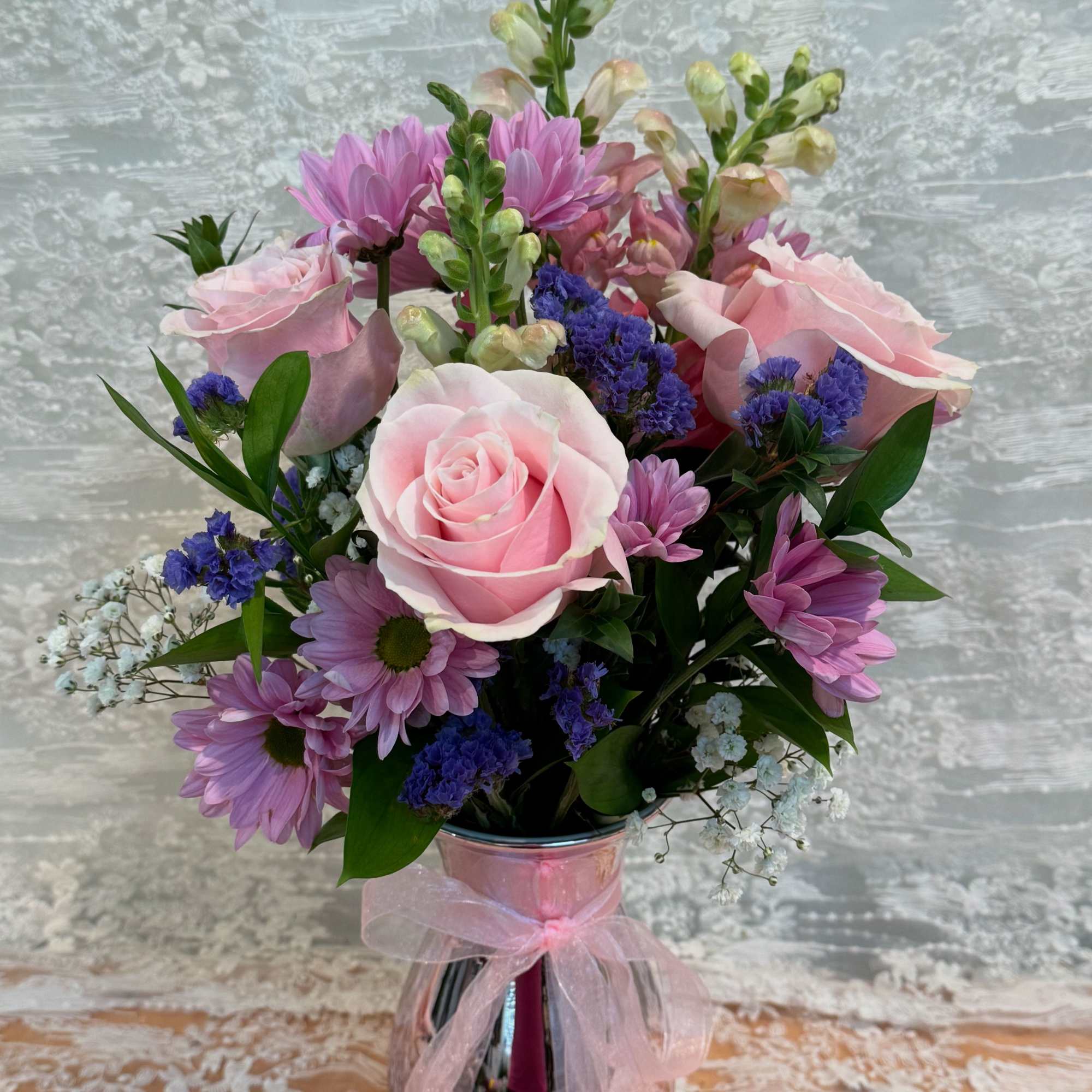 Arrangement filled with light pink roses, spray daisies and snapdragons. 